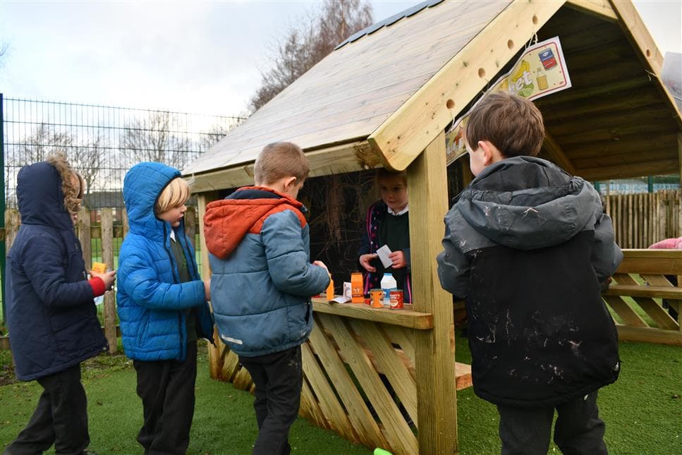 A group of children playing shops in their playhouse in their playground