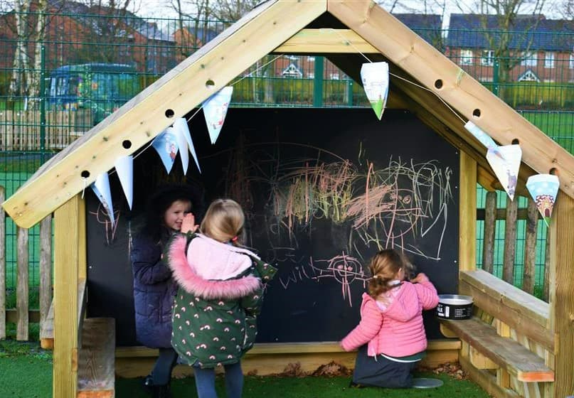 2 young girls drawing on the chalkboard in their playhouse