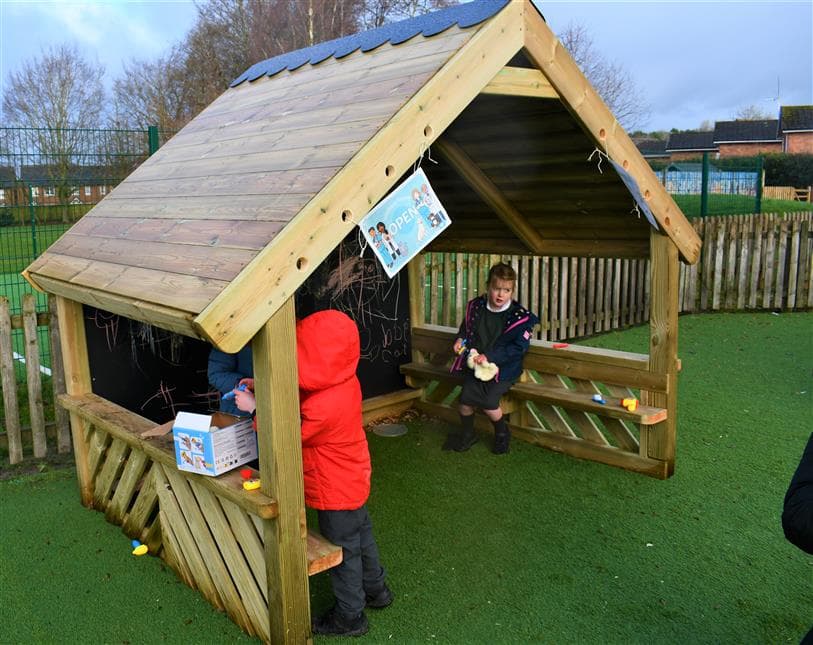 2 children sat in the playhouse in their playground