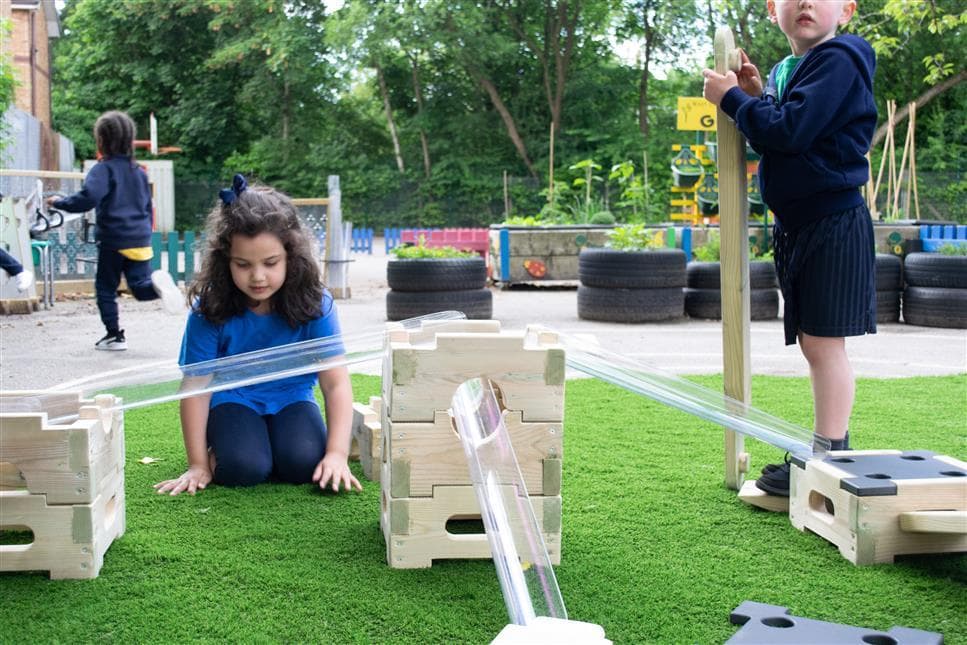 A young girl playing with the water channel stands on the water play play builder package