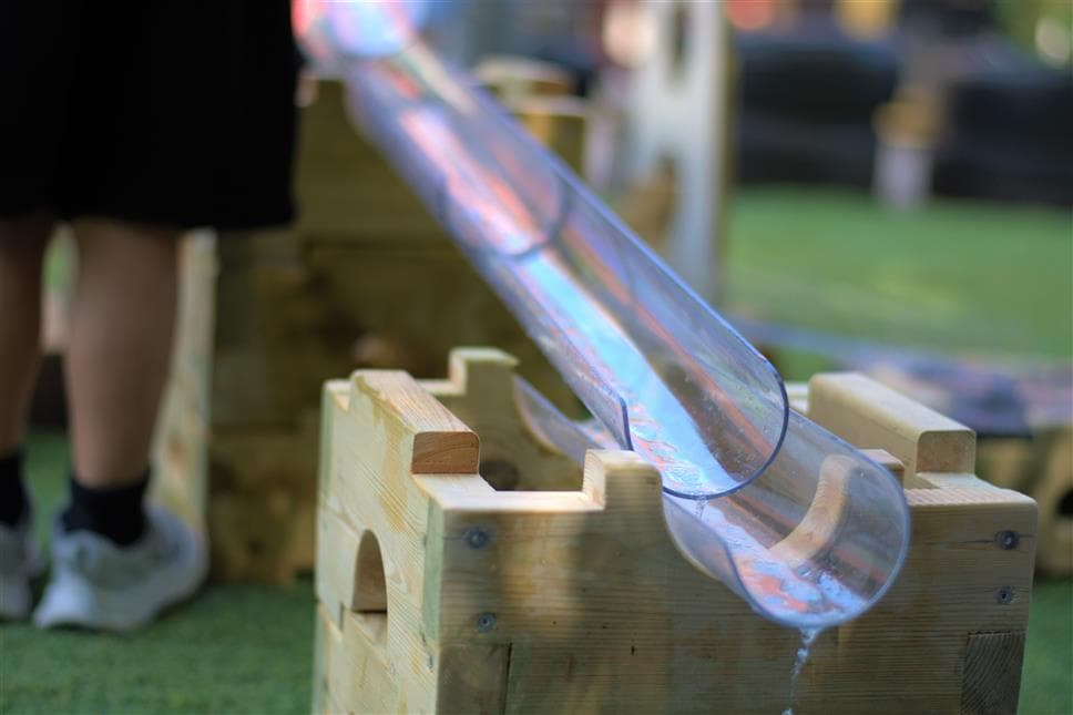 A side view of the water channel stands on the play builder wat play package