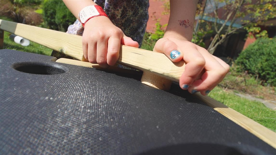 A child placing the button plank into the hole on the block