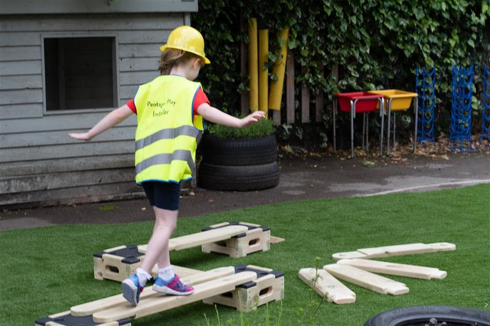 A young girl running across the play builder in her playground at school
