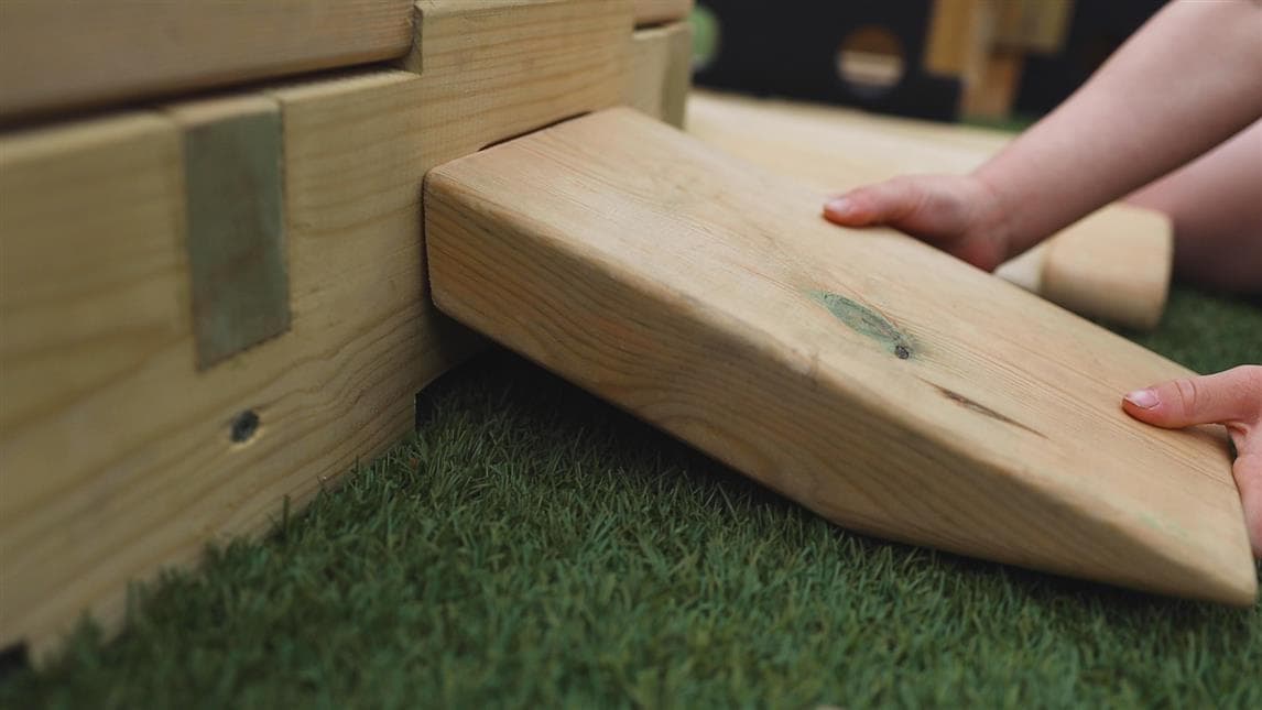 A close up of the small plank being pushed into the side of a block 