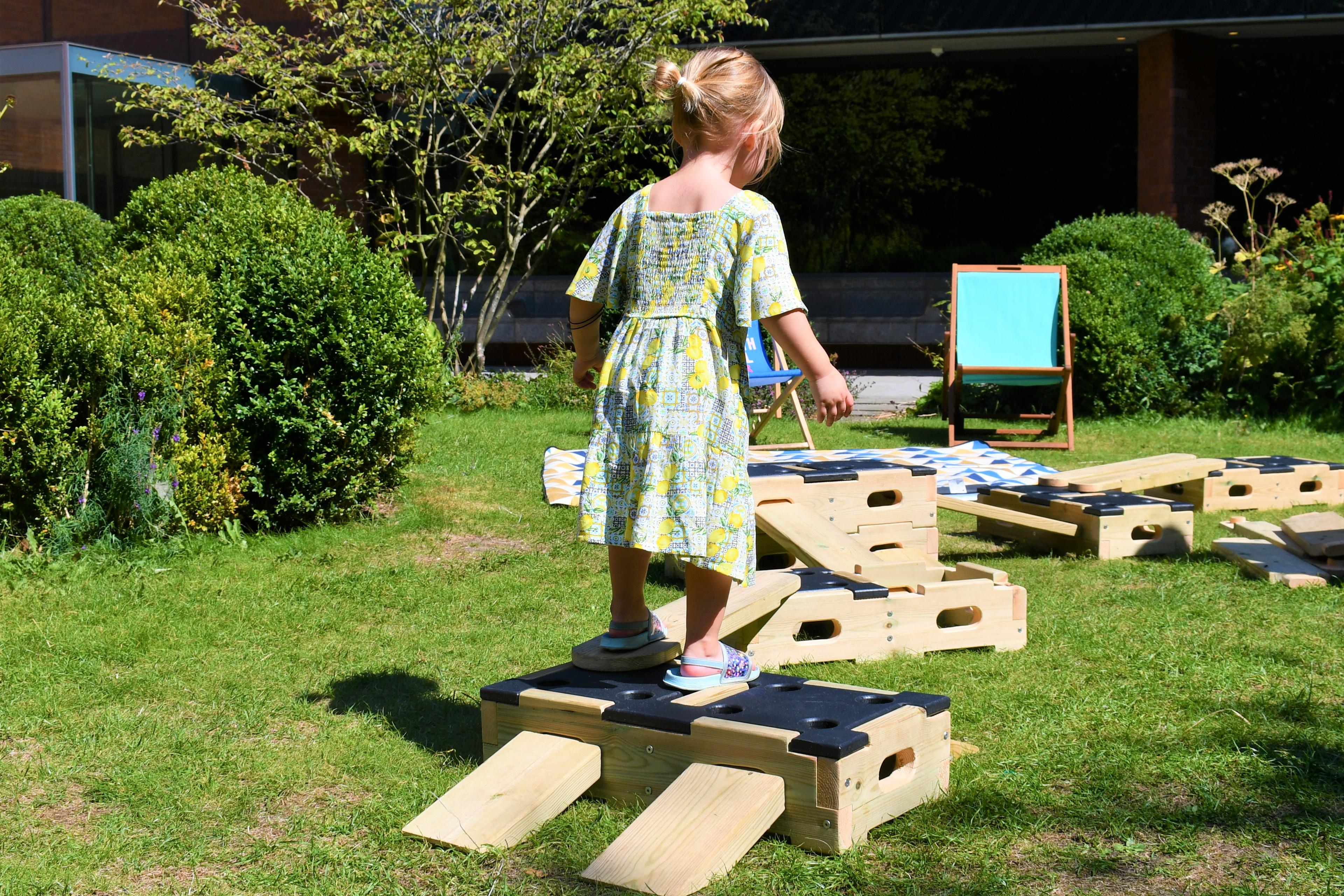 A young girl walking across the play builder