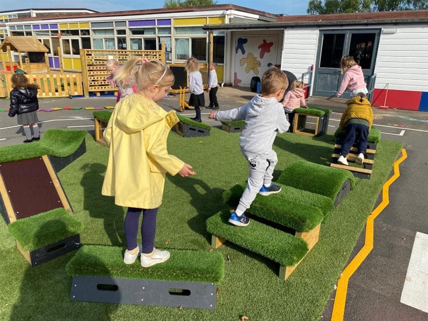A class of children walking around the blocks in the playground at school