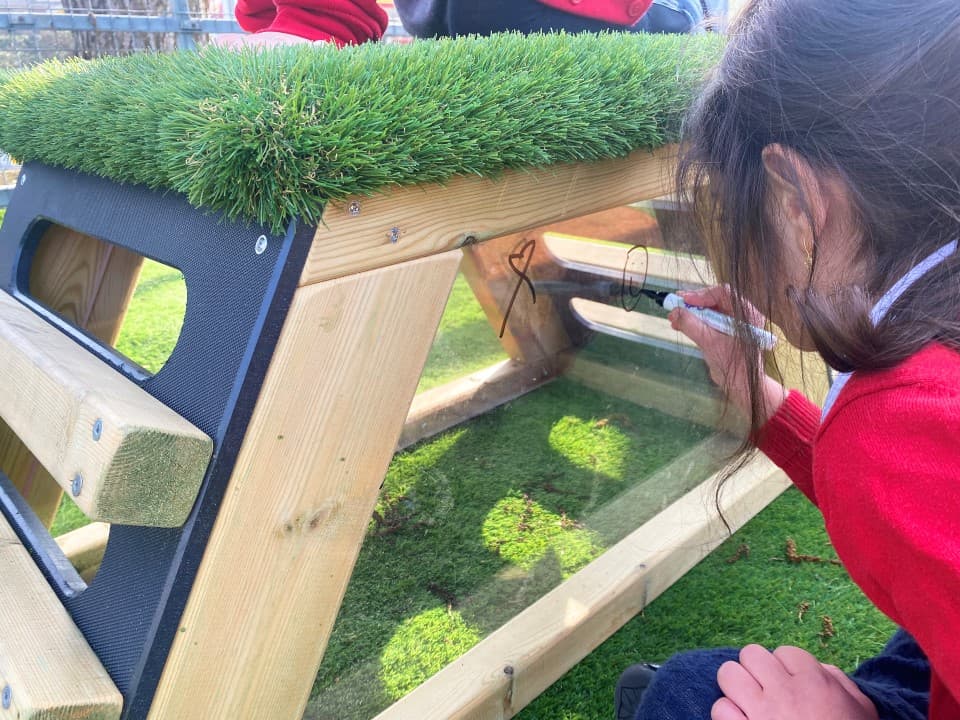 A young girl drawing on the side of the get set go block in her playground 