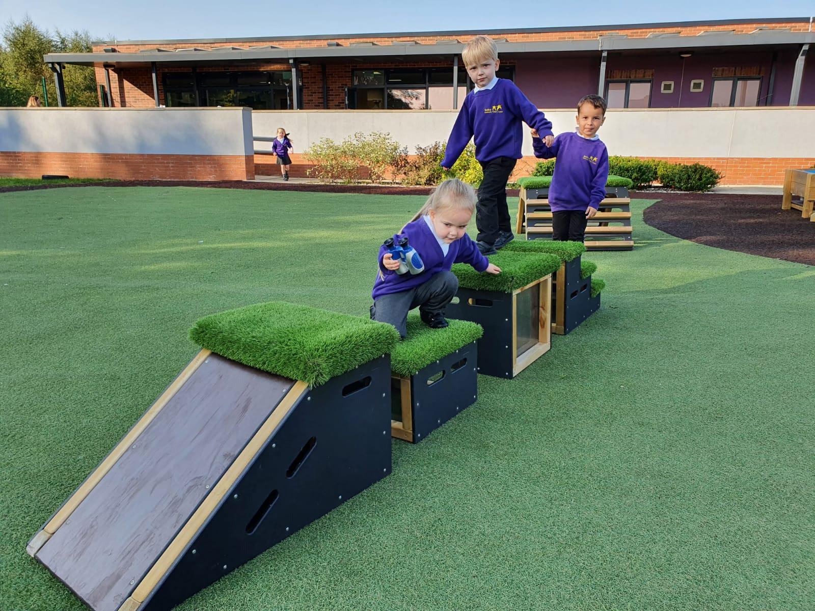 A group of children sliding down the blocks in their playground