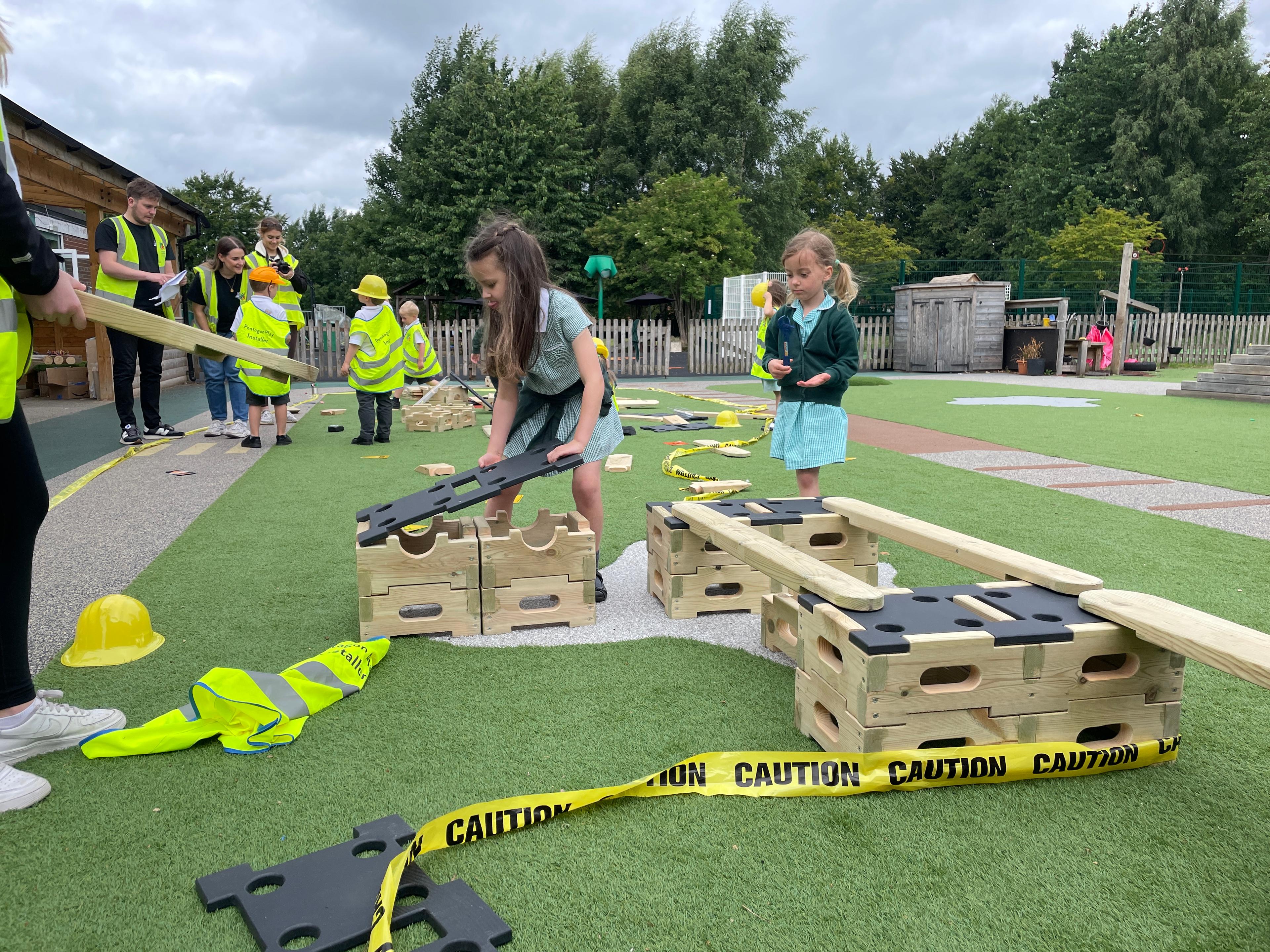 A young girl placing the lid of the play builder down whilst she is wearing a yellow hard hat 