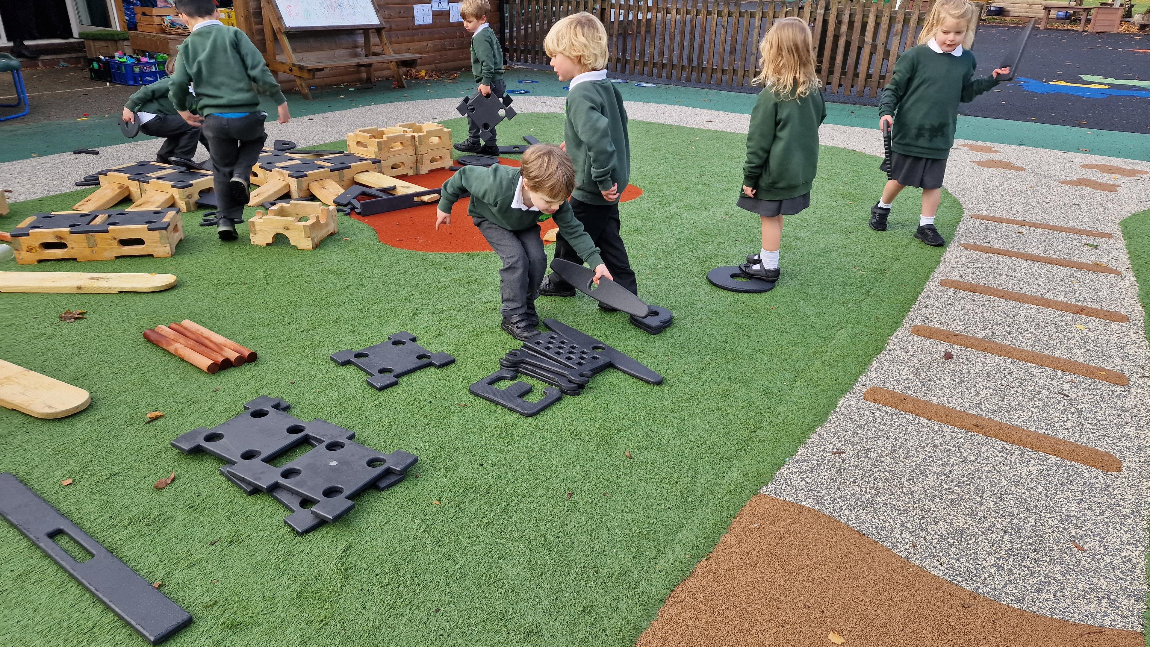 4 children picking up the role play pieces and putting them in a pile on their playground