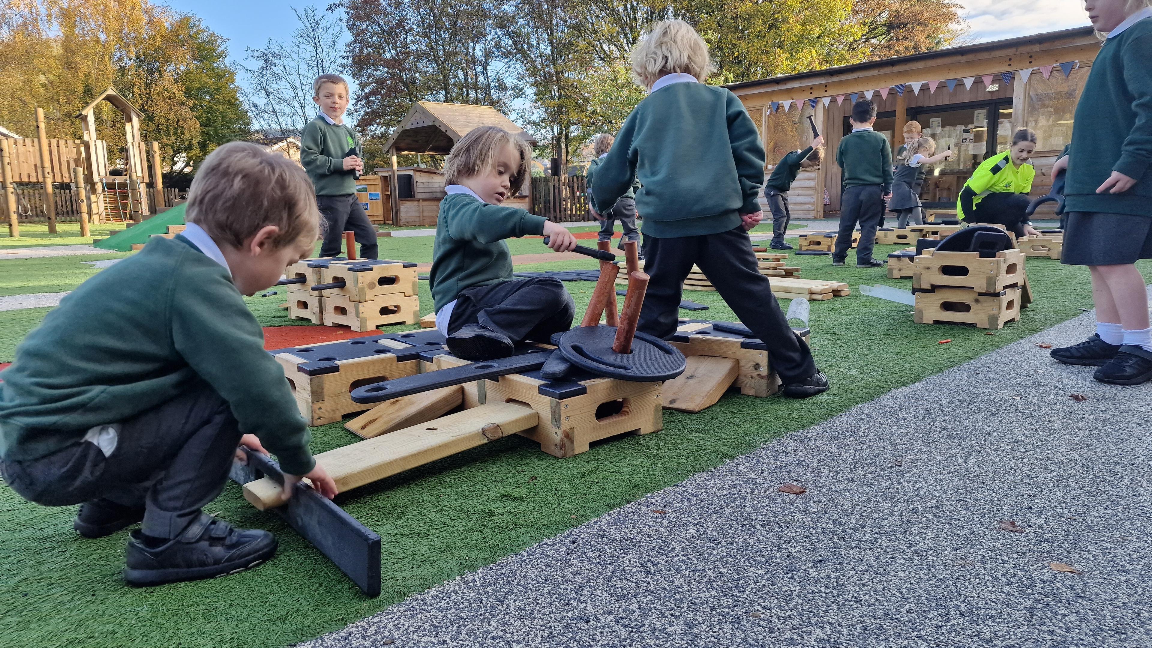 A side view of children sat on the blocks in their playground using the role play set 