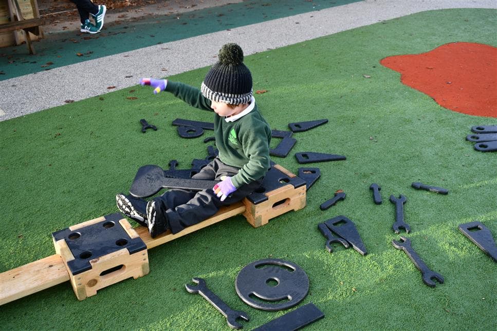 A young boy pretending to be on a boat in his playground