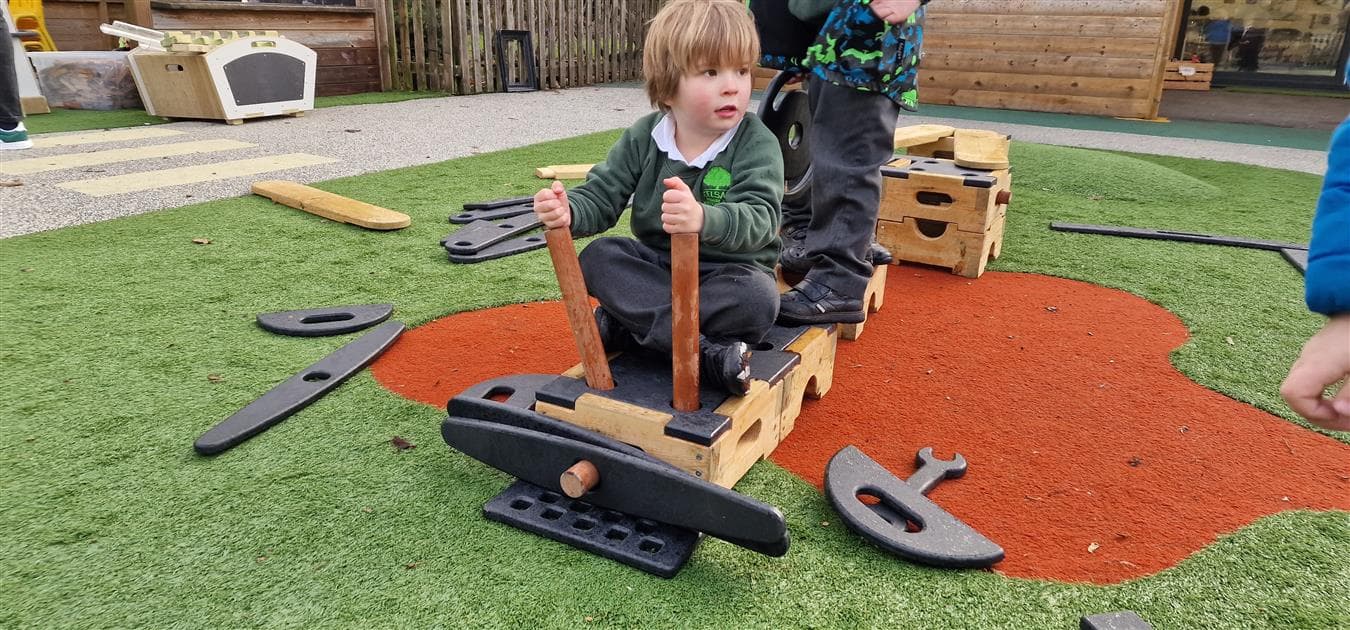 A young boy pretending to drive a train in his playground