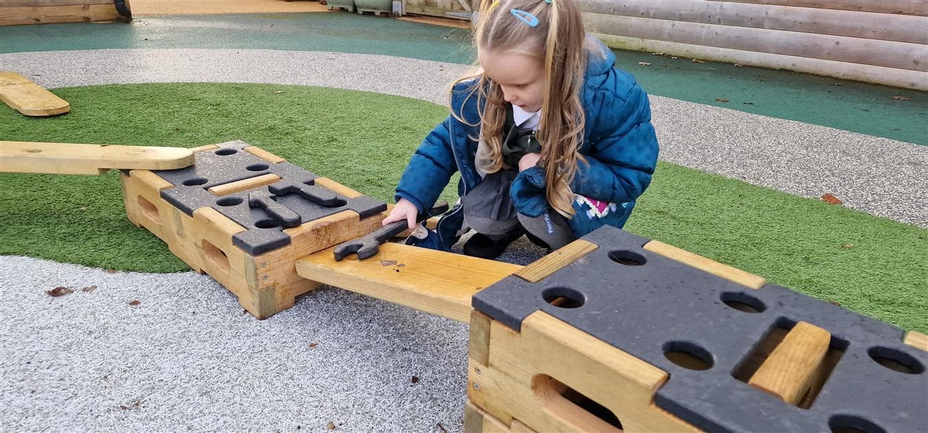 A girl using a spanner as a role play item in her playground