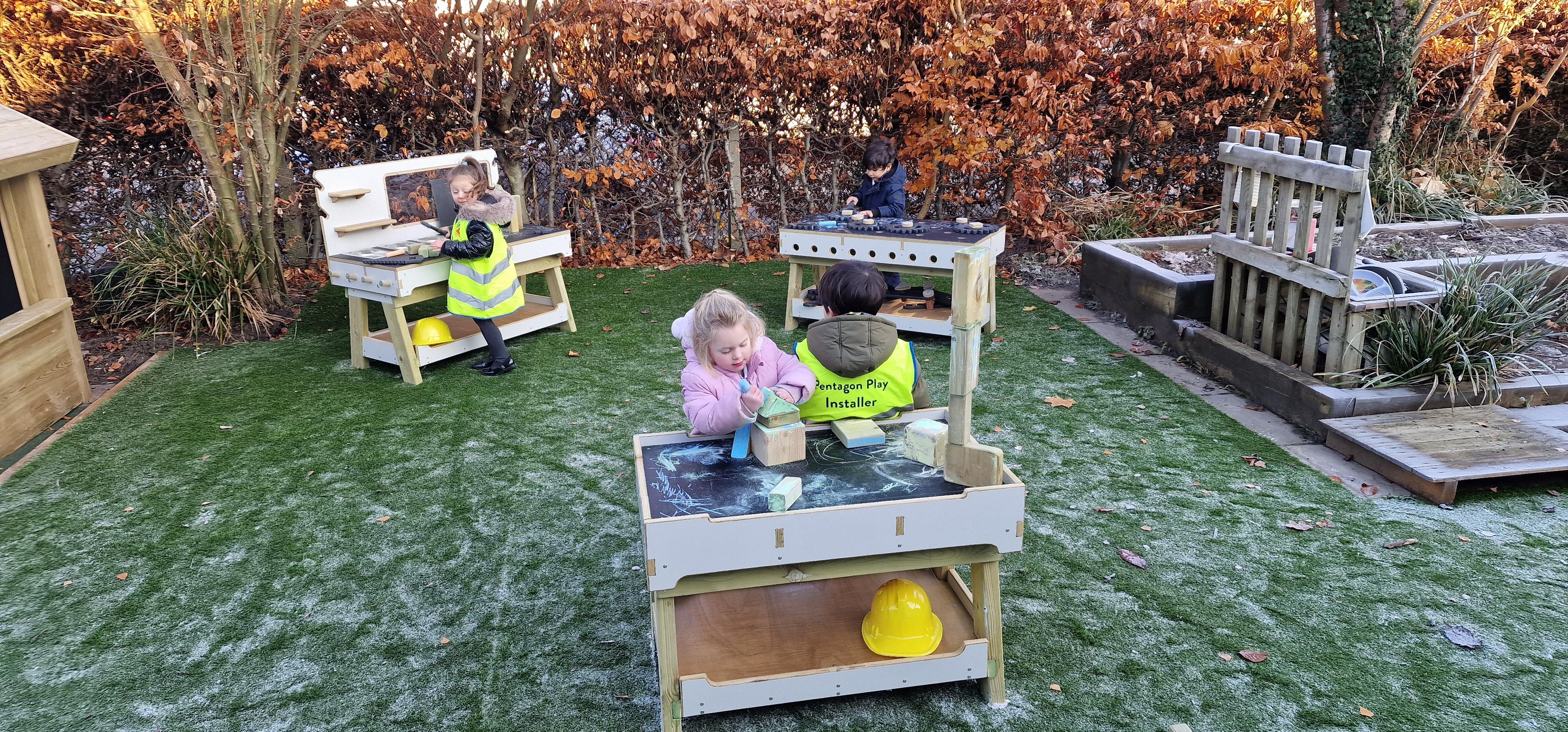 children using the work bench and construction table in their playground