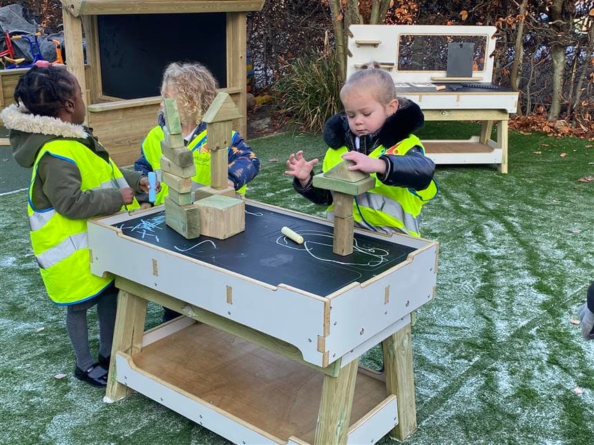 Children using blocks on the work bench in their playground 