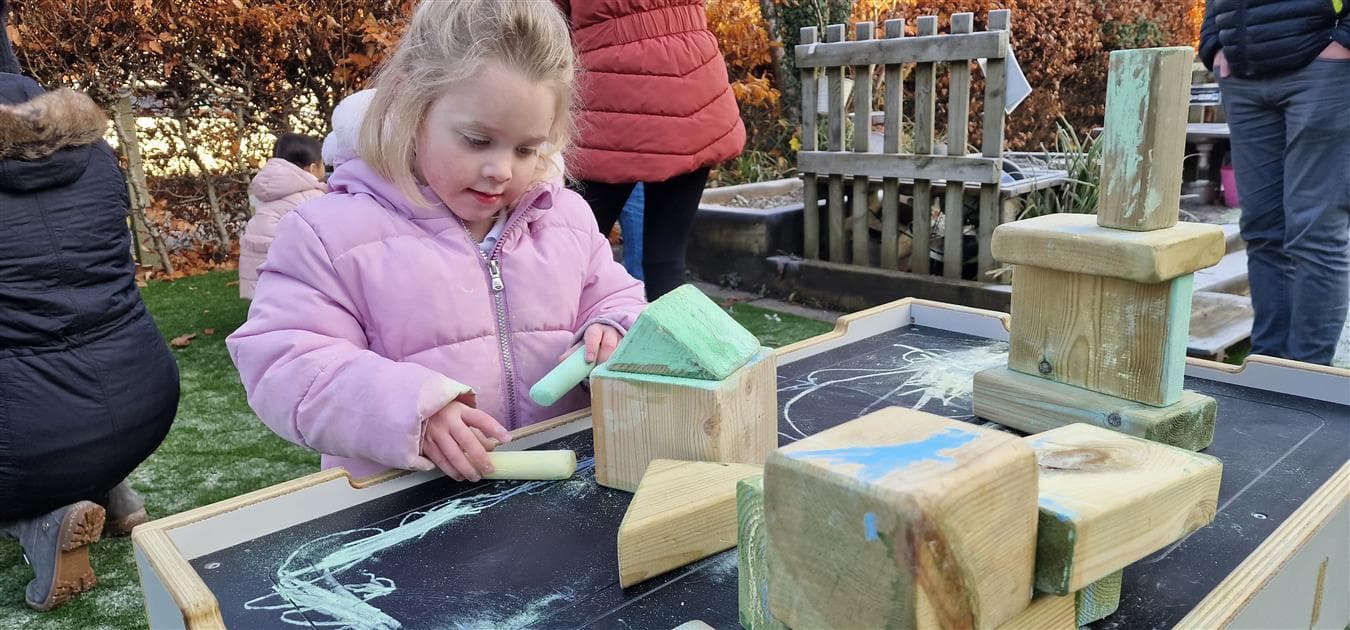 A early years girls using blocks on the work bench in her playground at school