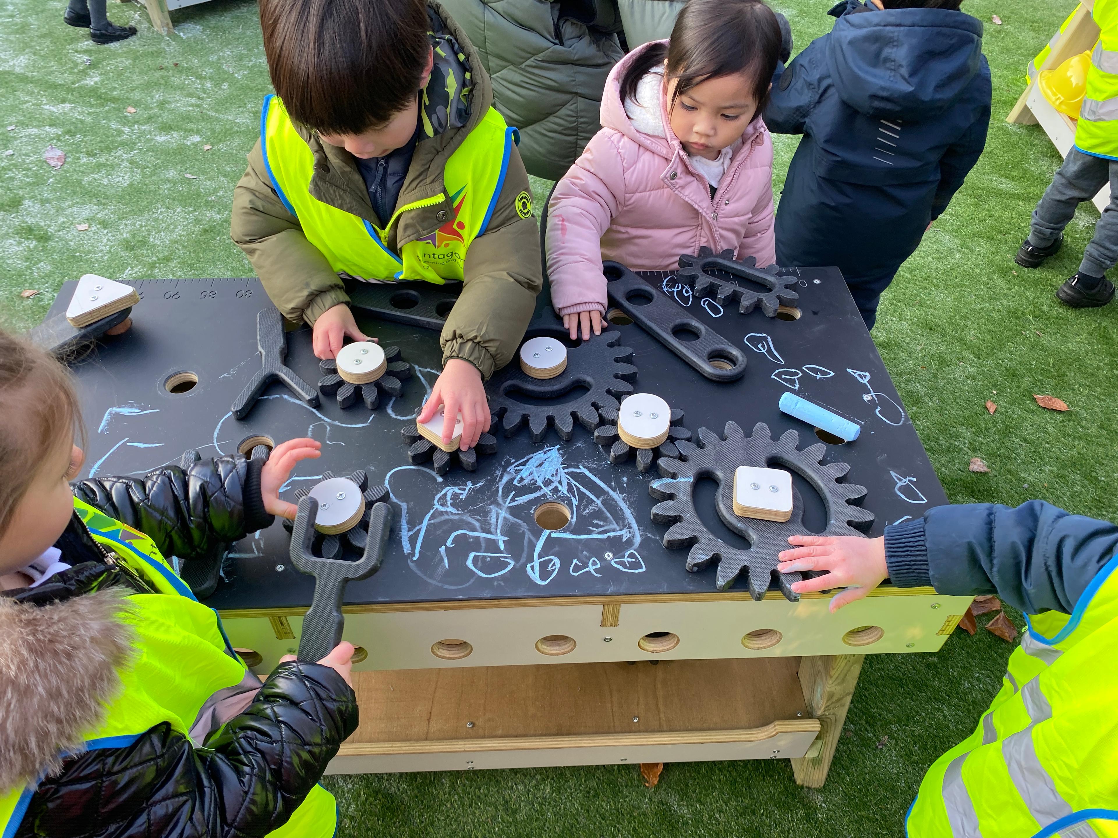 A group of children using the STEAM table in their playground at school