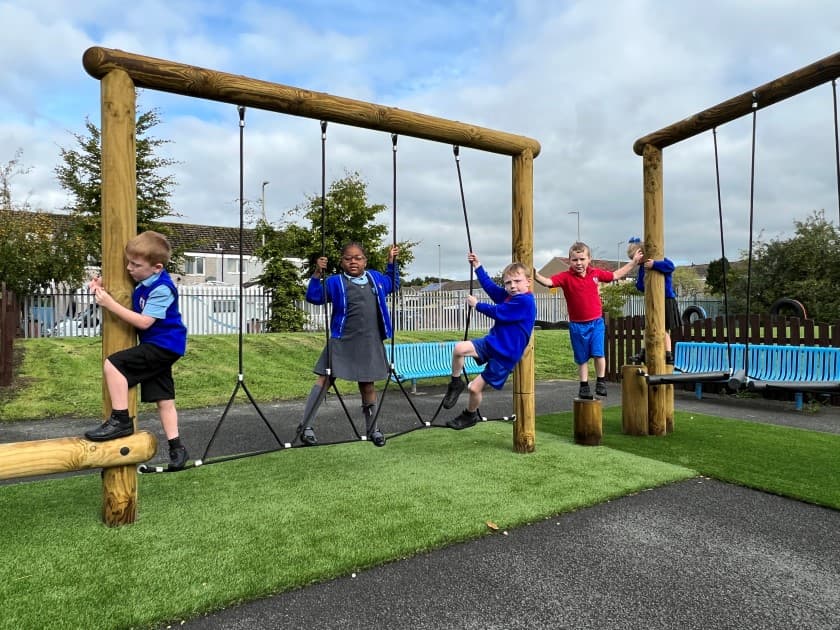 A class of children climbing across the rope traverse 