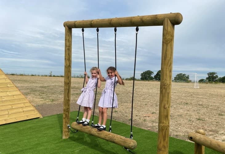 2 girls balancing on the trim trail in their primary school