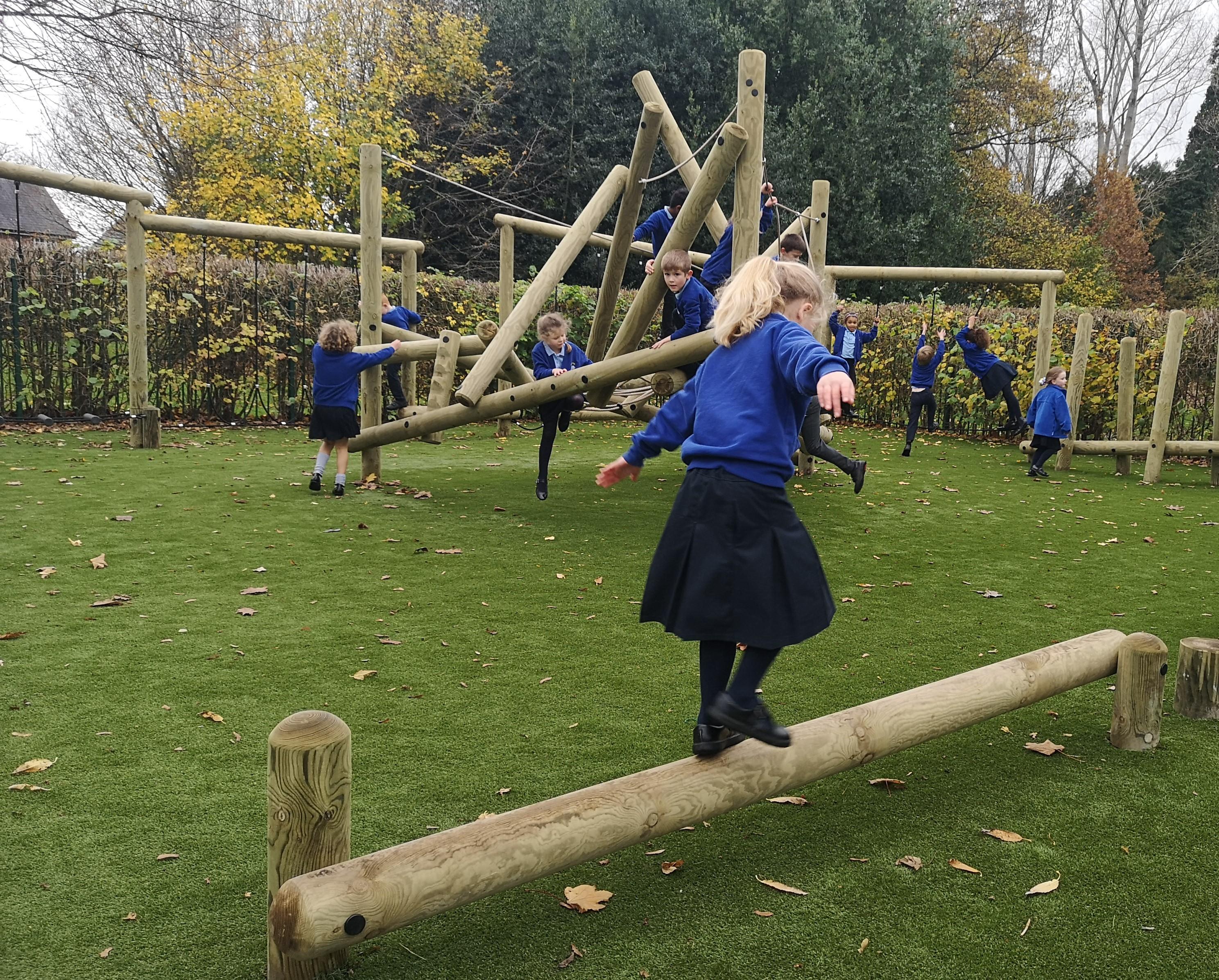A girl walking and balancing on the balance beam in the playground