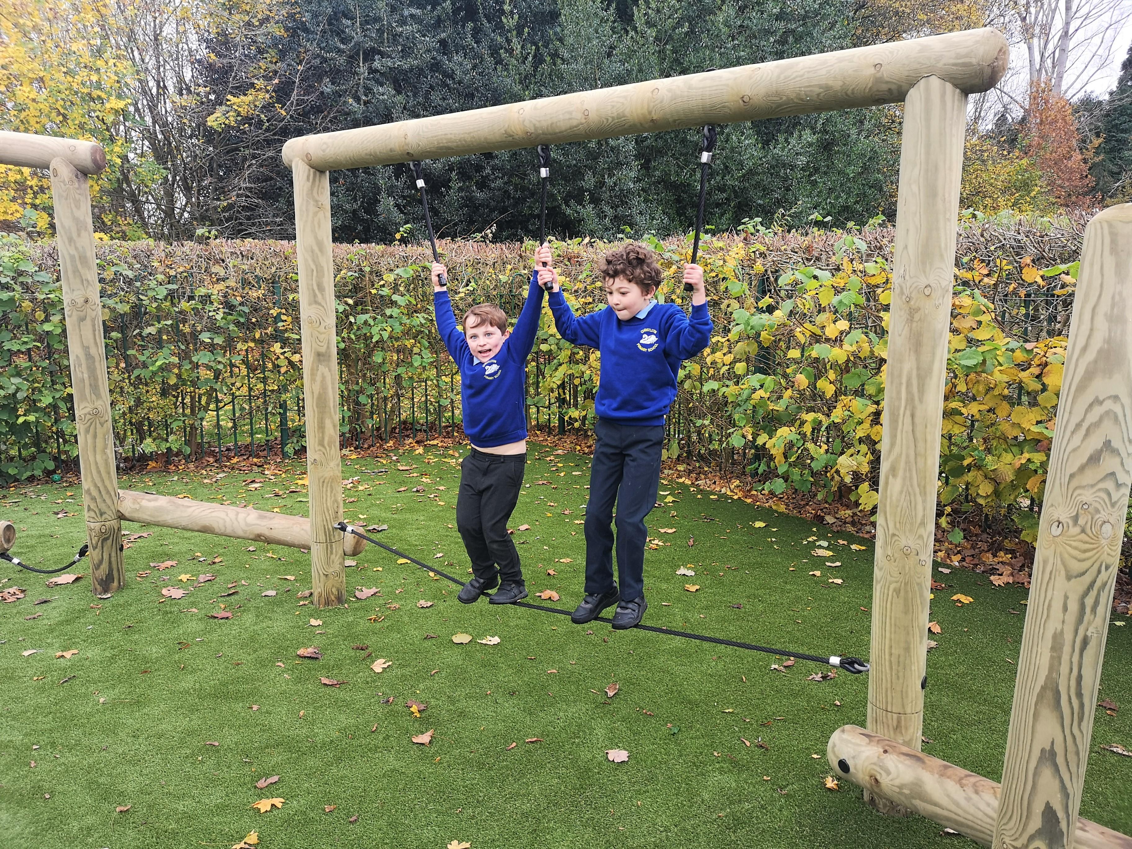 2 young boys balancing on the tight rope trim trail in their playground