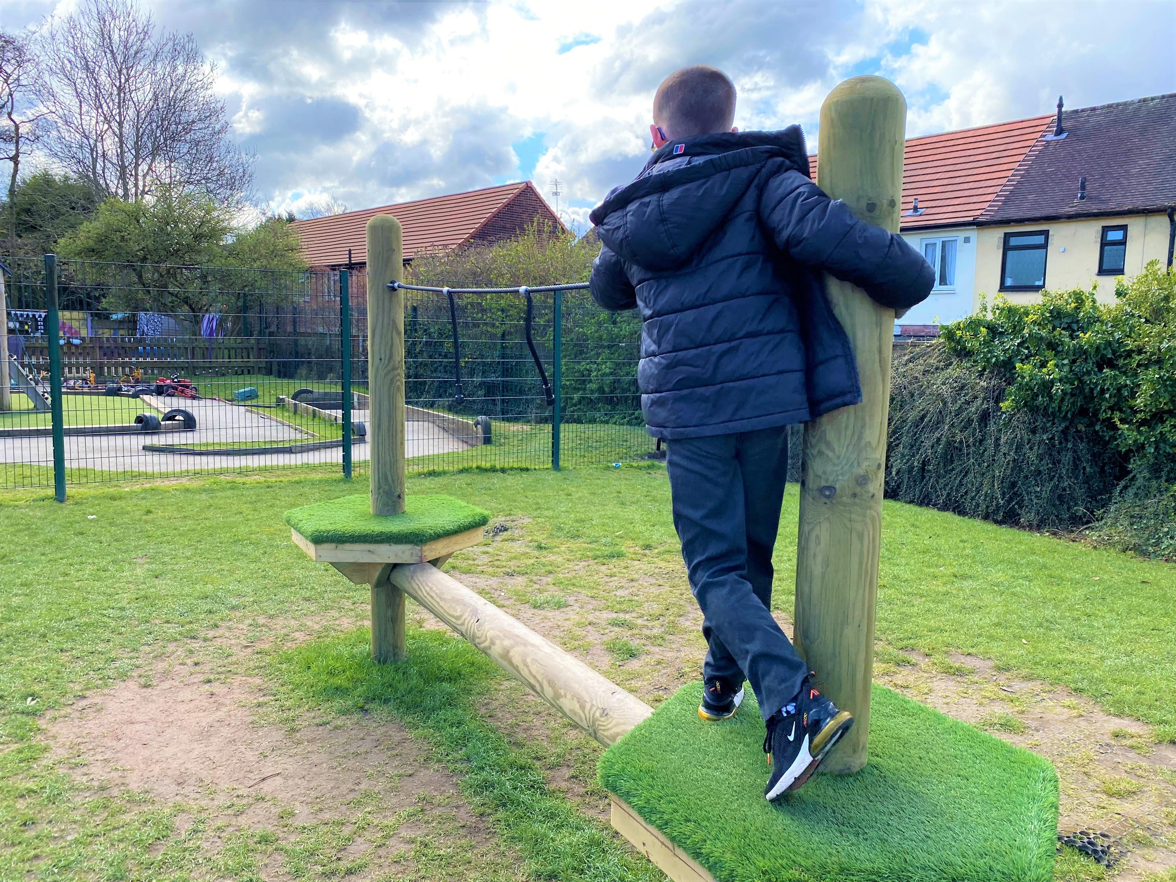A young boy standing on the platform on his trim trail in his primary school