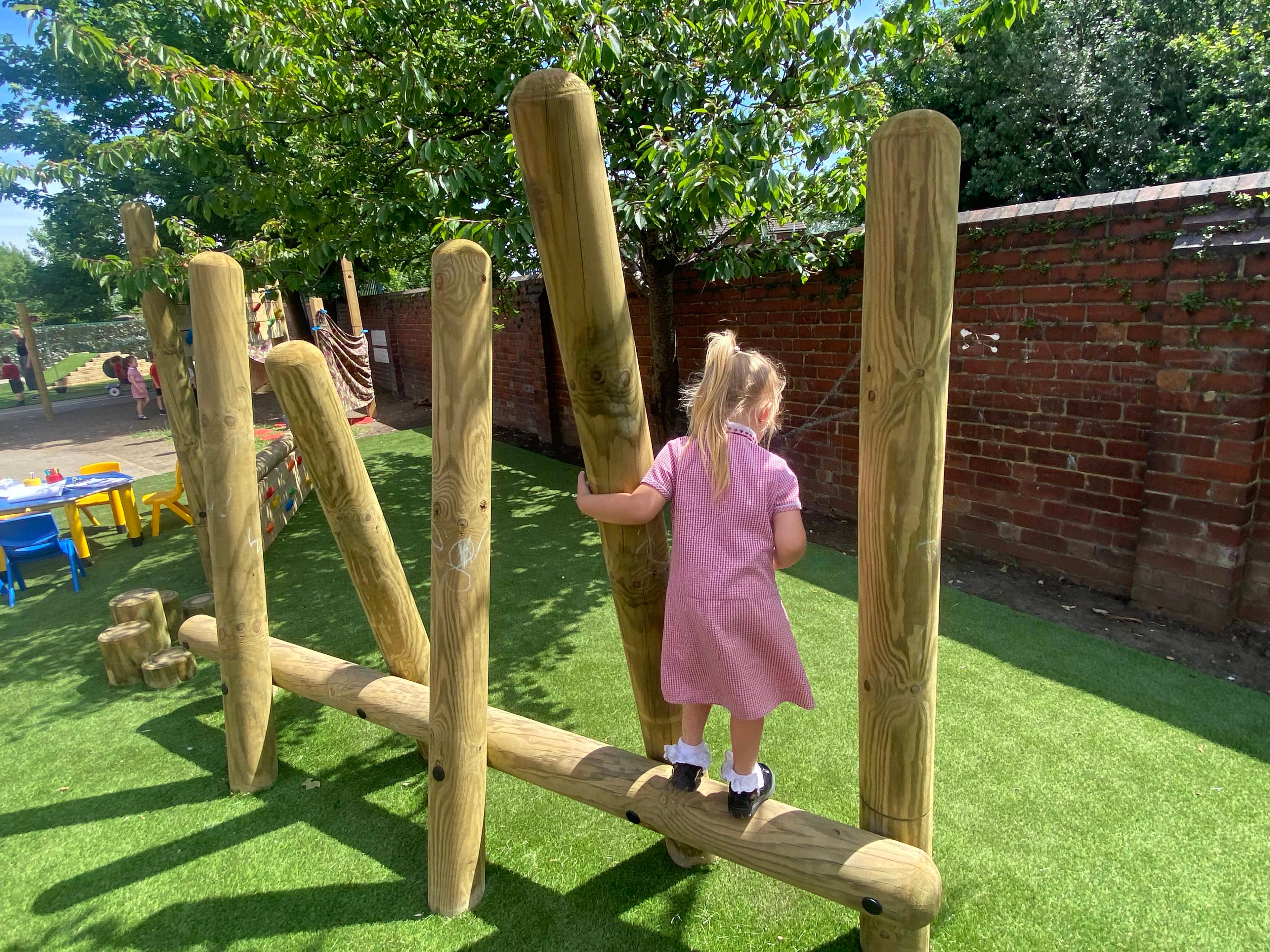 A young girl stepping onto the climbing poles in her school