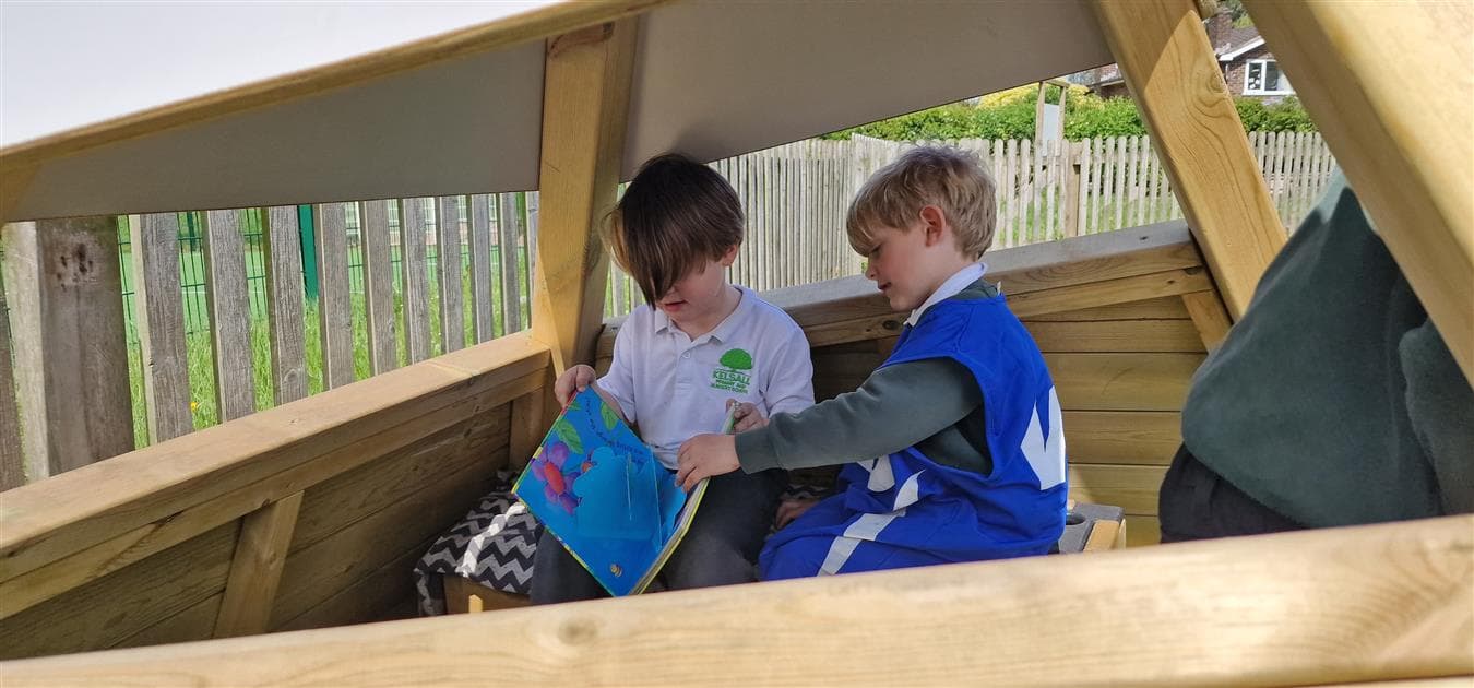 two children reading stories in the wigwam in their playground