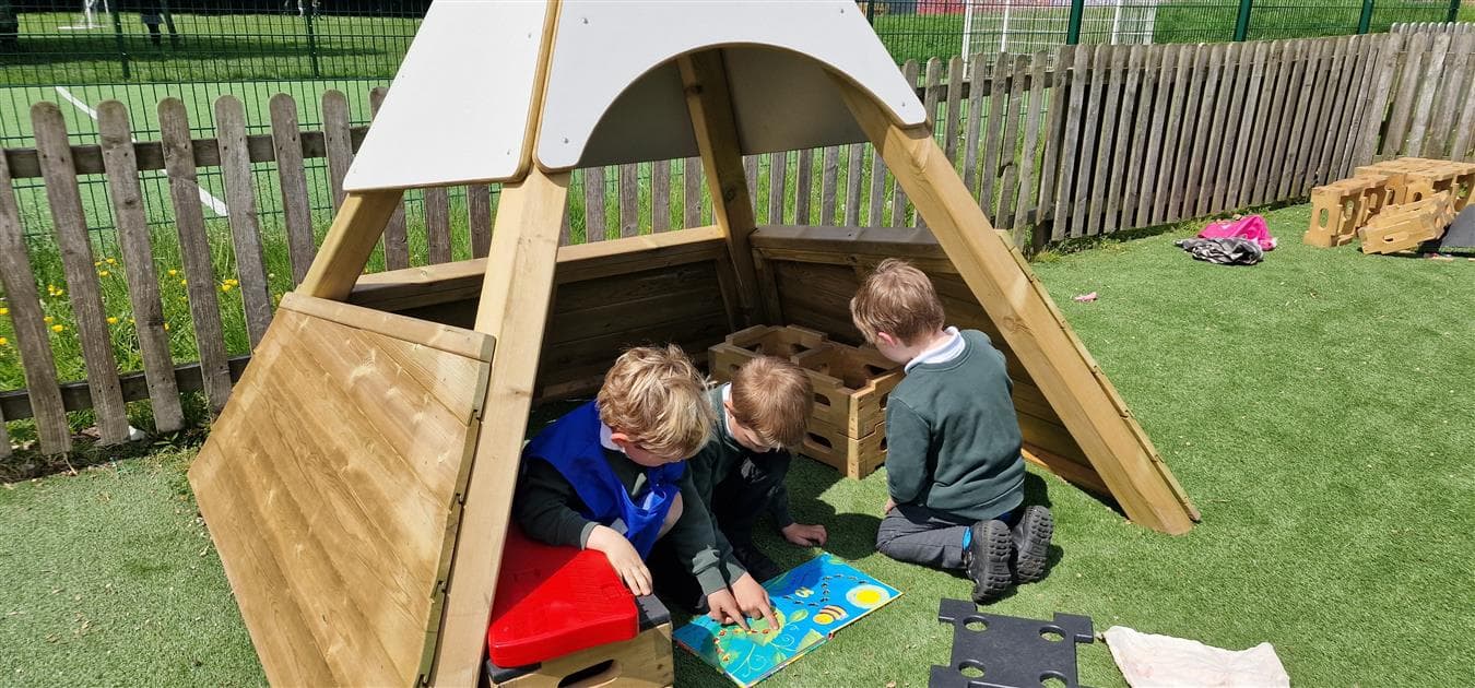 A group of children playing under the wigwam in their playground