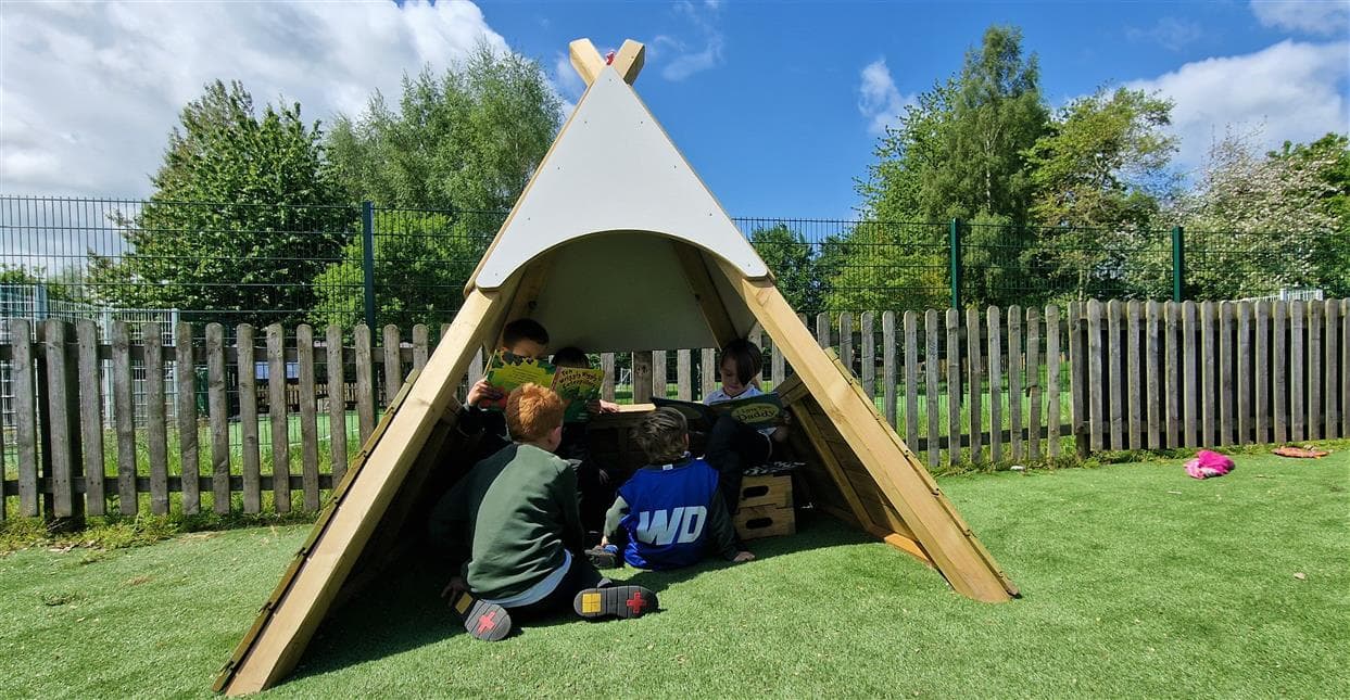 A class of children sat underneath the wigwam in their school