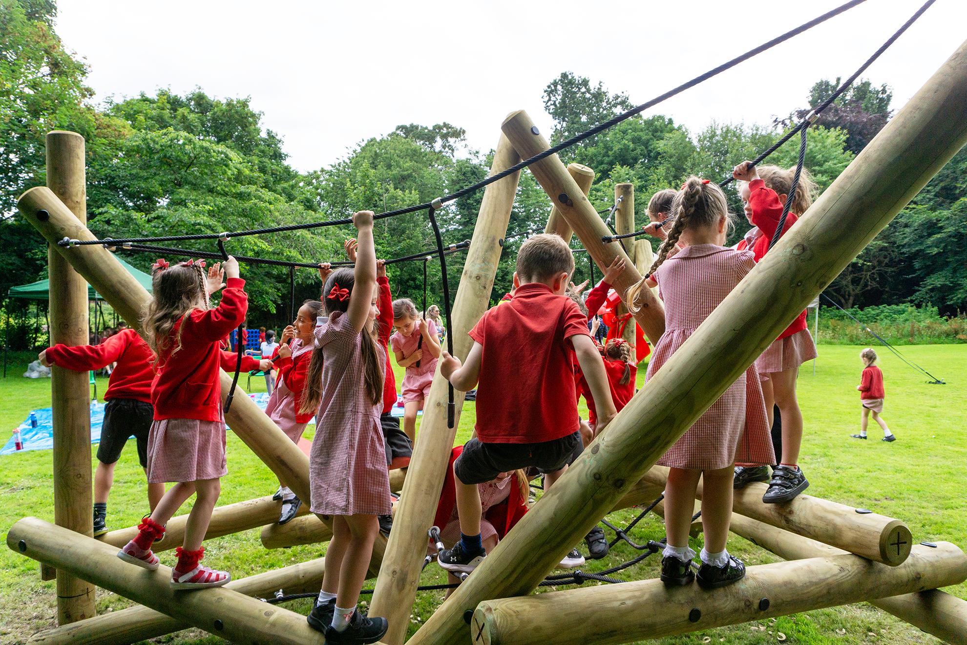 A large group of early years children are exploring the Latrigg Mountain Climber.