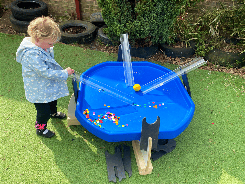 A young girl playing with the water channels in the tuff spot tray