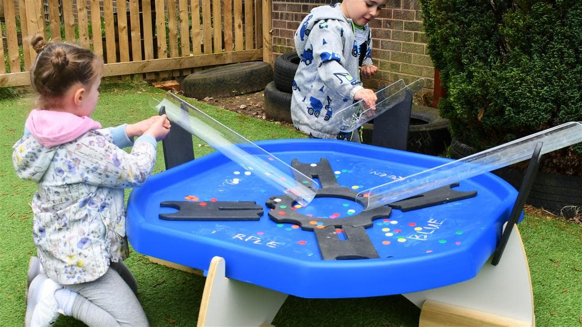 2 children playing on the tuff spot tray in their playground