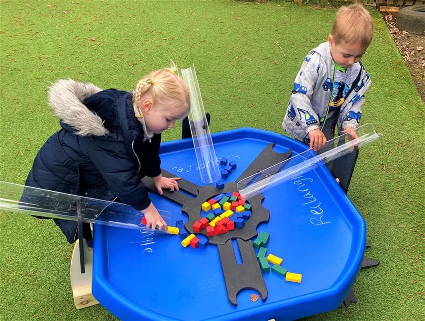 2 children playing with the movable tuff spot tray