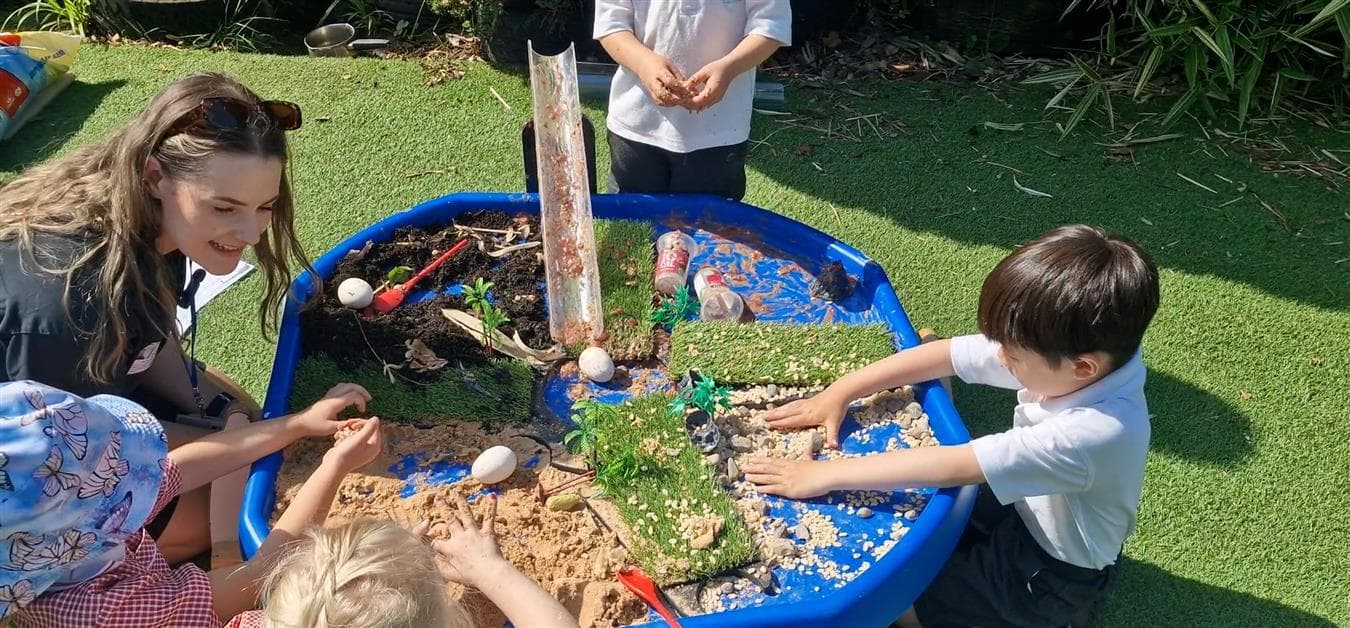 A class of children playing on the tuff spot table in their playground 