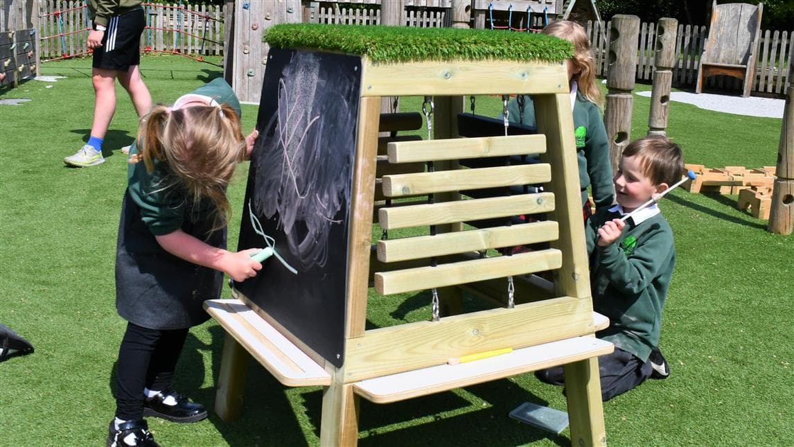 Children using the music and art easel in their playground setting