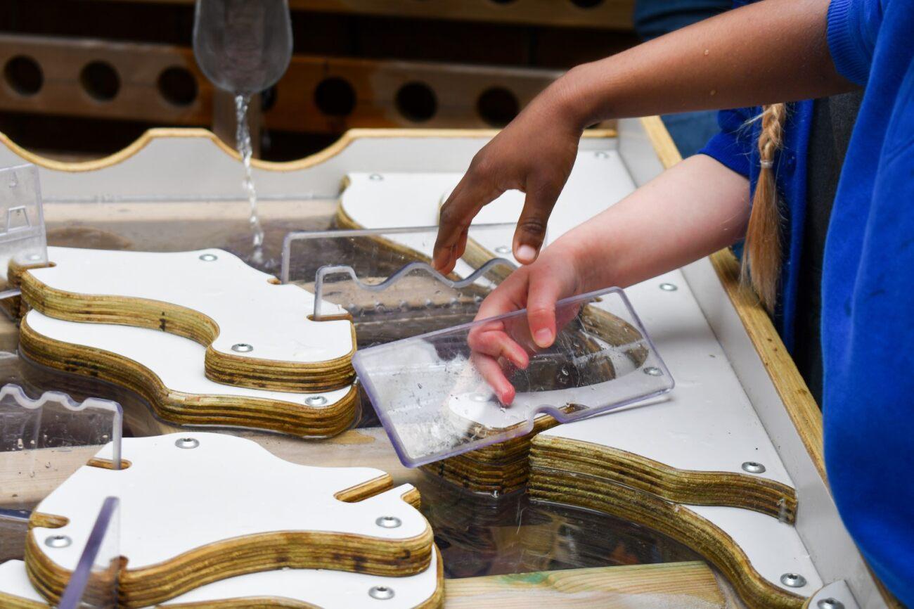 A close up of children's hands moving some of the clear dams