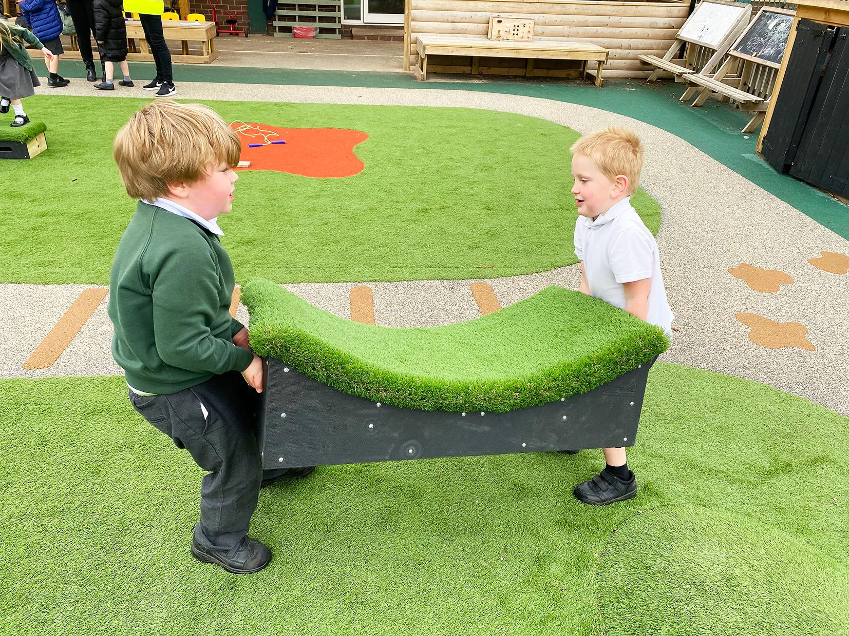 2 little boys from Kelsall Primary School are carrying a Get Set, Go! Block that looks like a half pipe skate ramp. They are lifting it with ease.