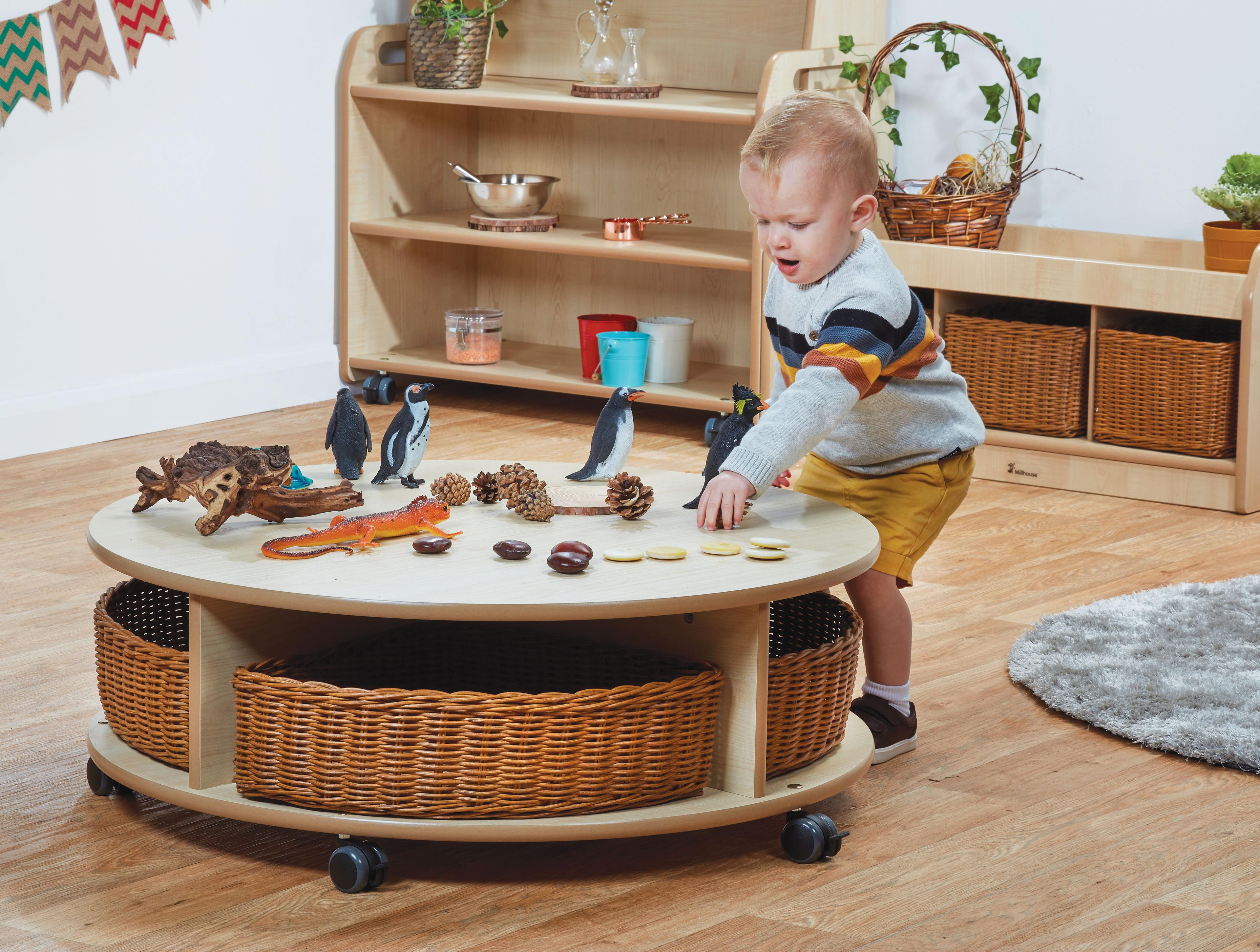 A young boy using small world resources on a Single Tier Mobile Circular Storage Unit with 4 Baskets, in a classroom.