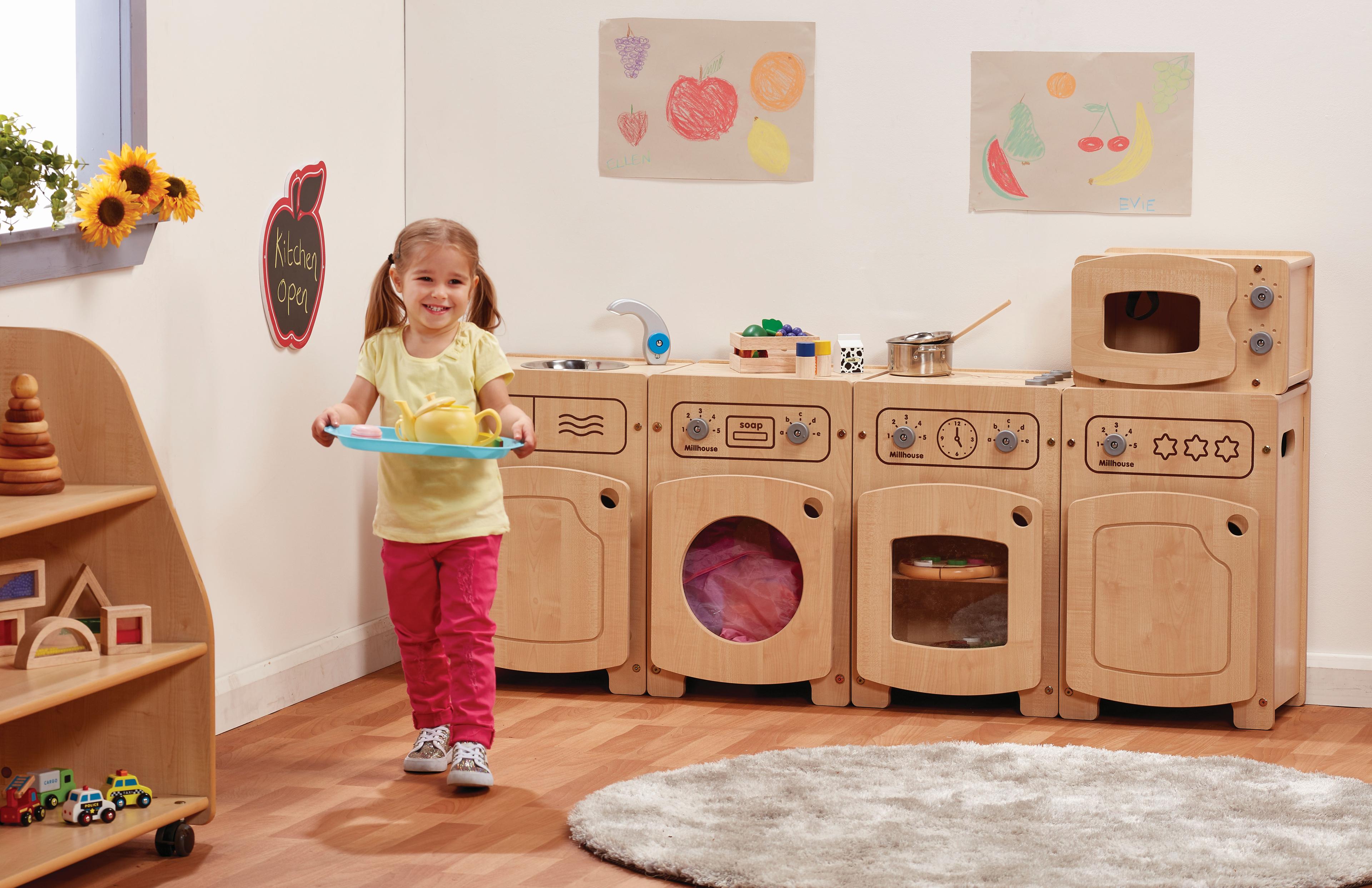 A young girl has made some play food using the Stamford Kitchen Set (Microwave, Sink, Fridge, Washer & Cooker). 