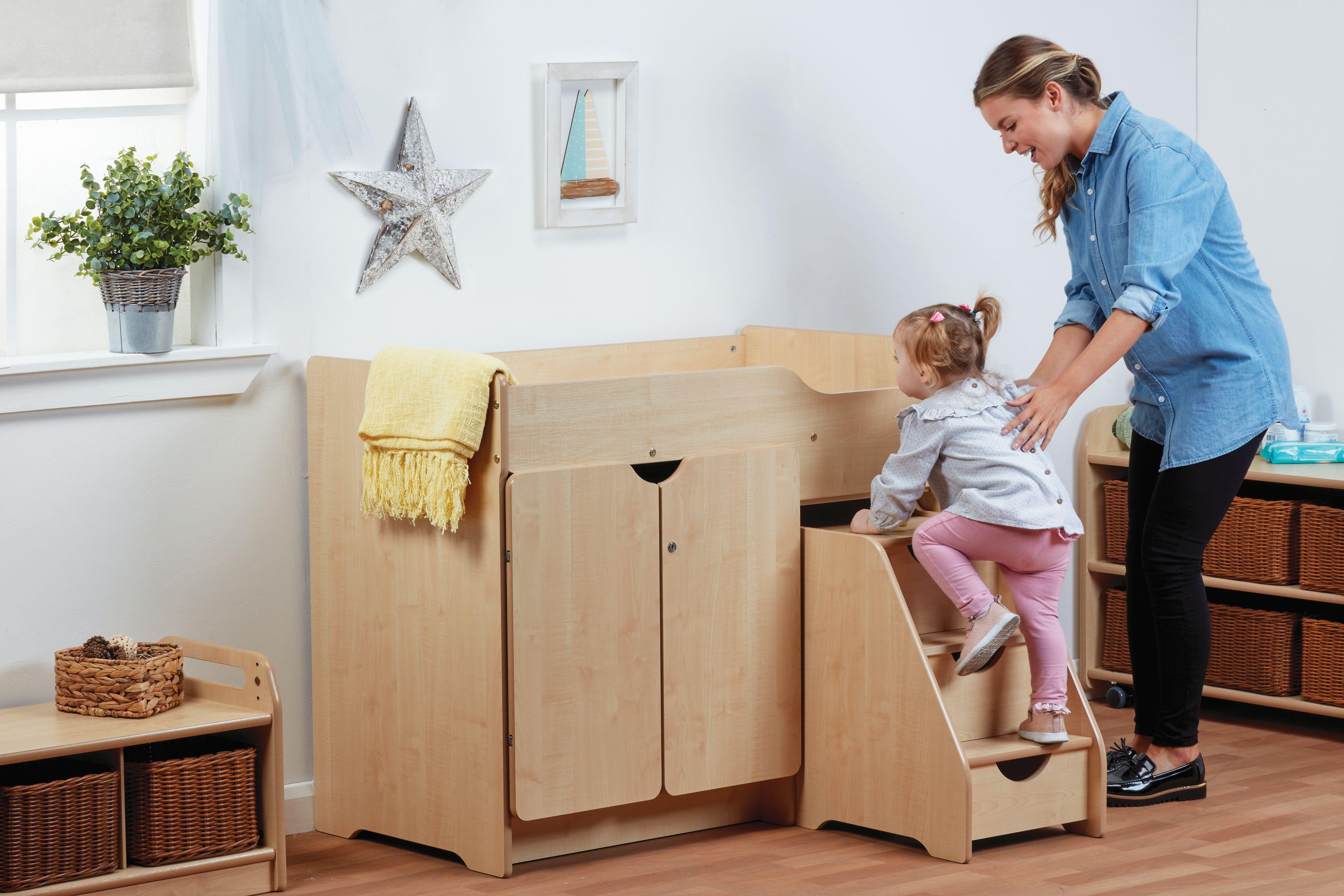 A Nursery practitioner helps a young girl up the Stepped Baby Changing Unit.
