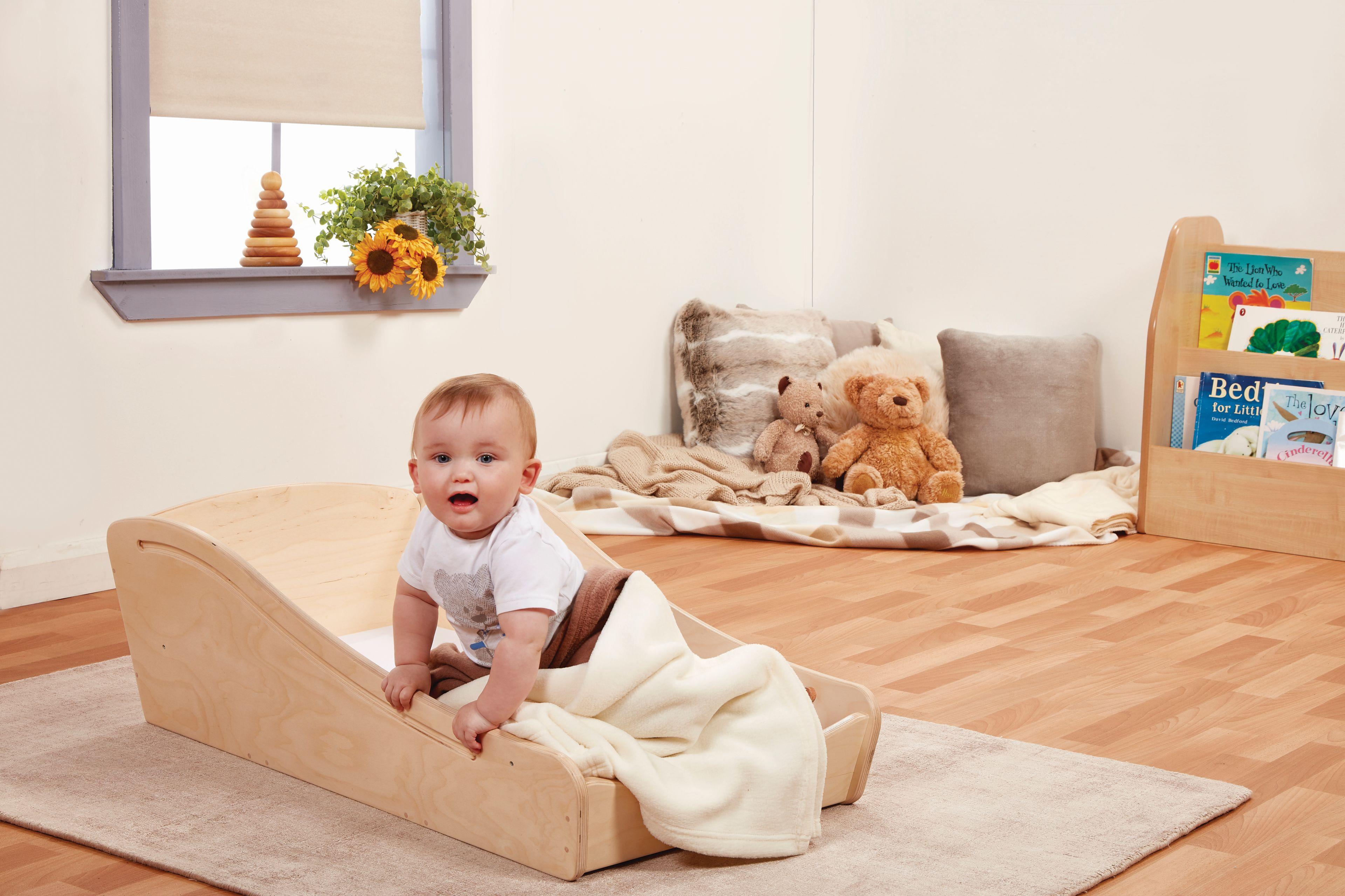 A baby is sat in the Sleep Pod which is in a classroom. 