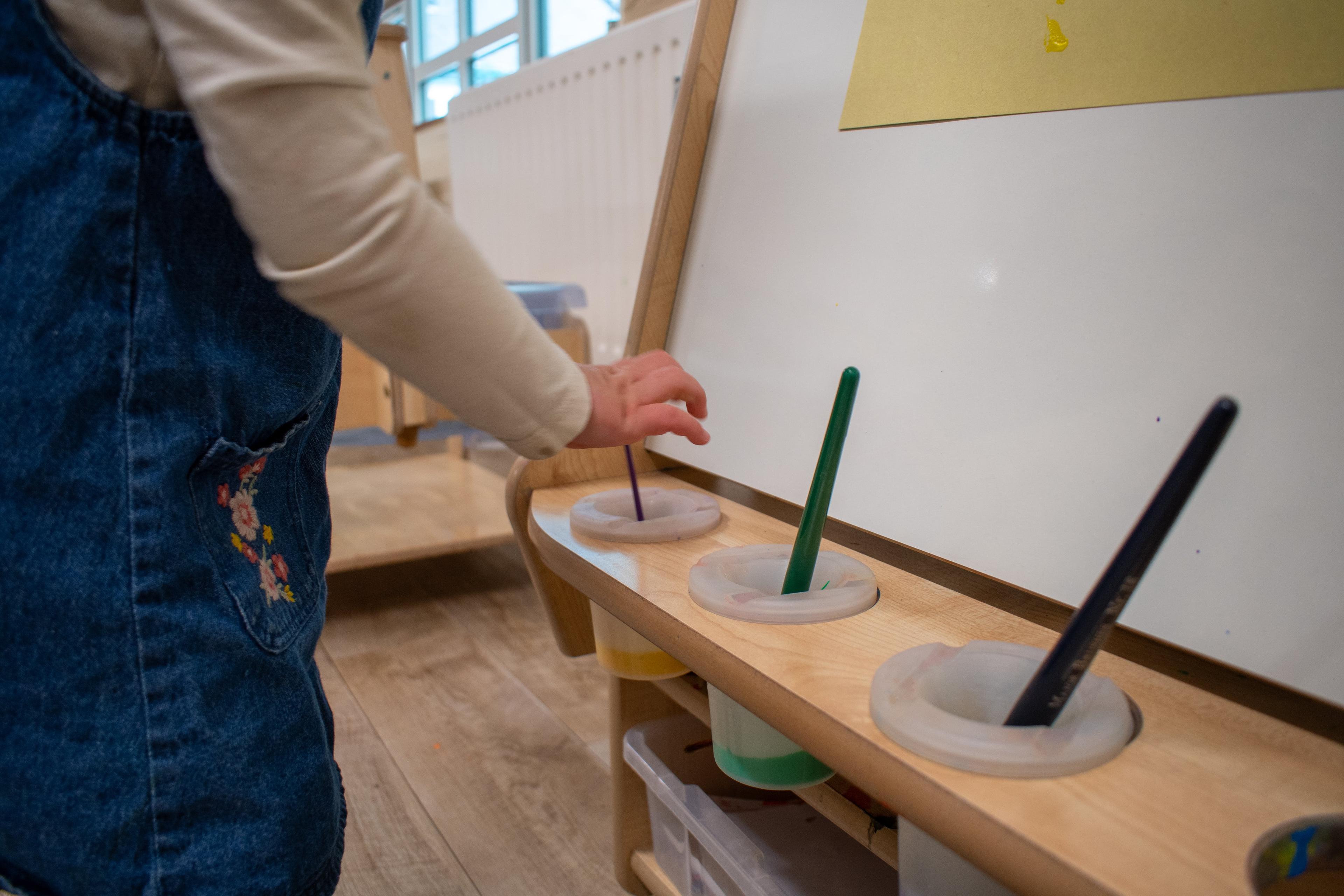 A close up of a child choosing her paintbrush for her Millhouse Easel