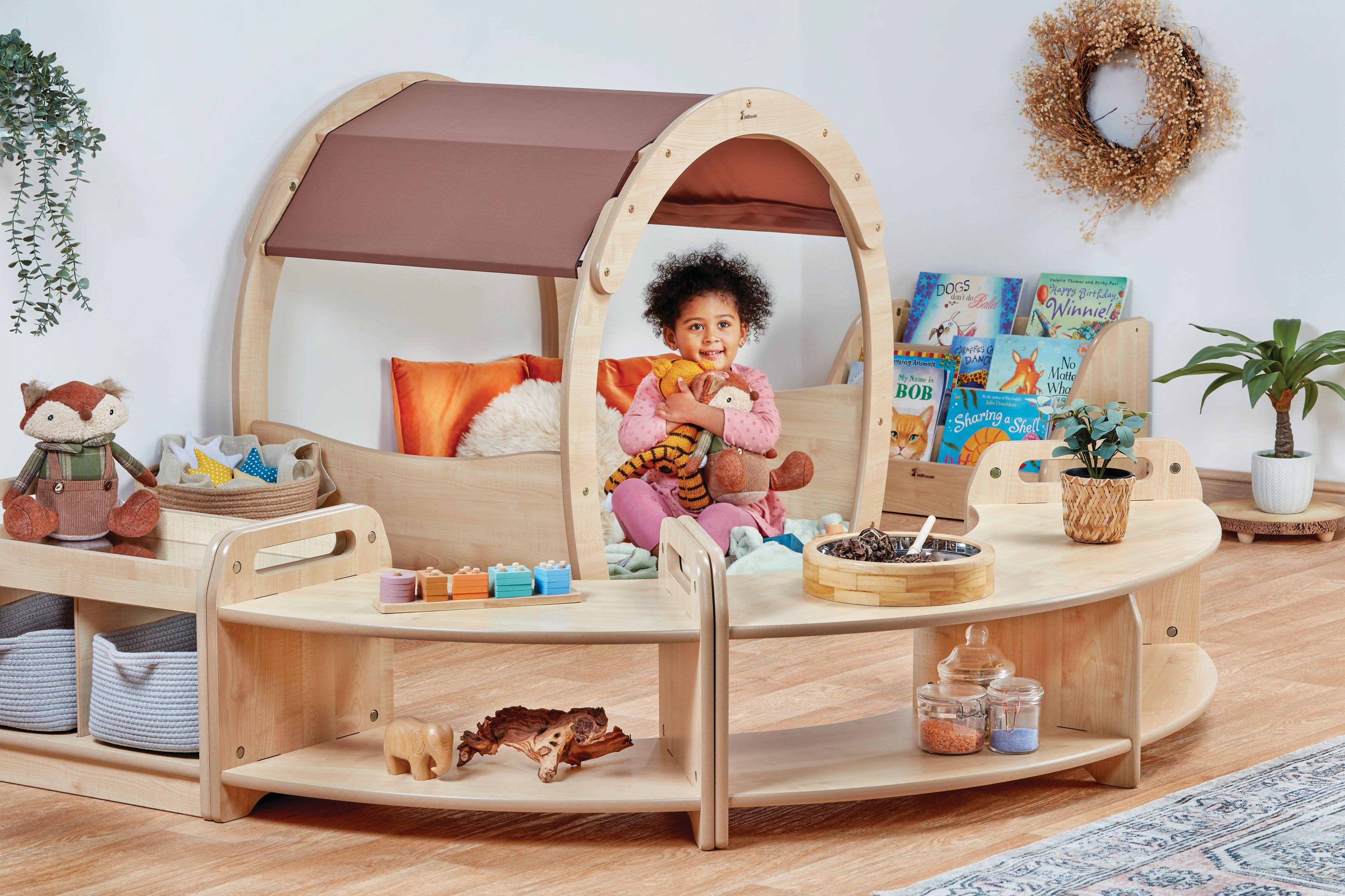 A young girl is sat playing in the Curious & Cosy Zone, in a classroom.