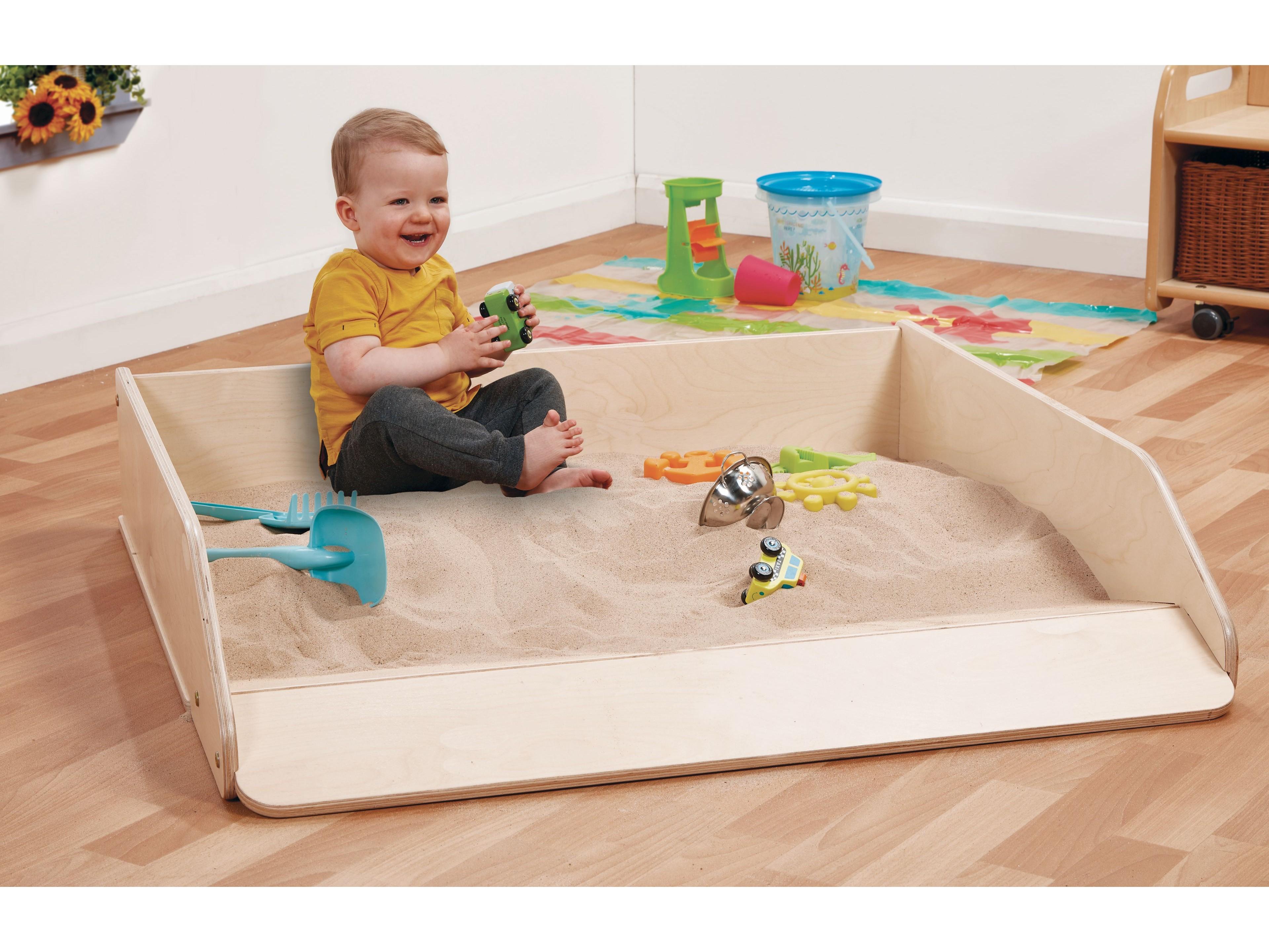millhouse sand pit with baby playing in the sand and sand accessories surrounding