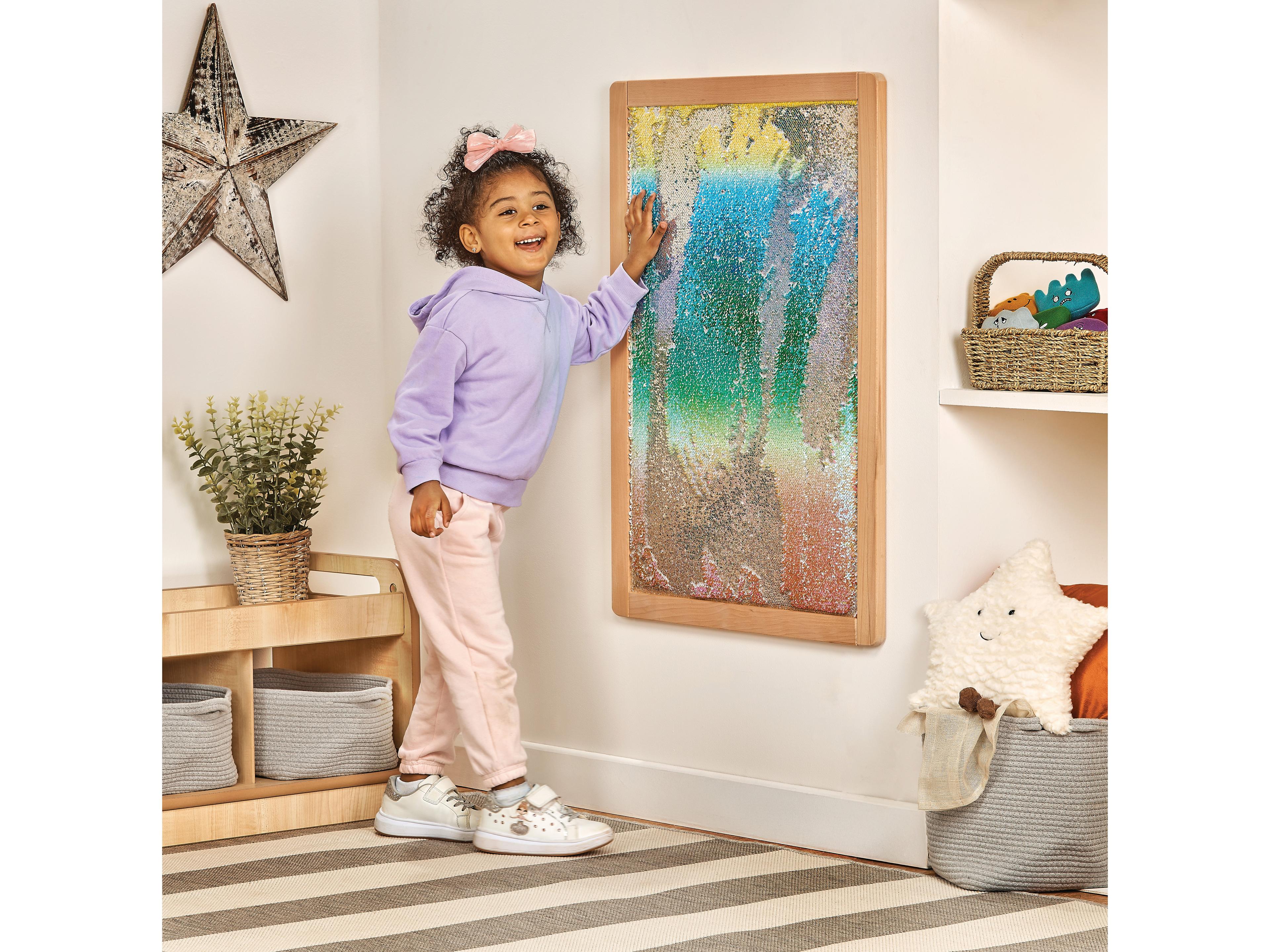 millhouse sequin panel on wall with child brushing their hand up against