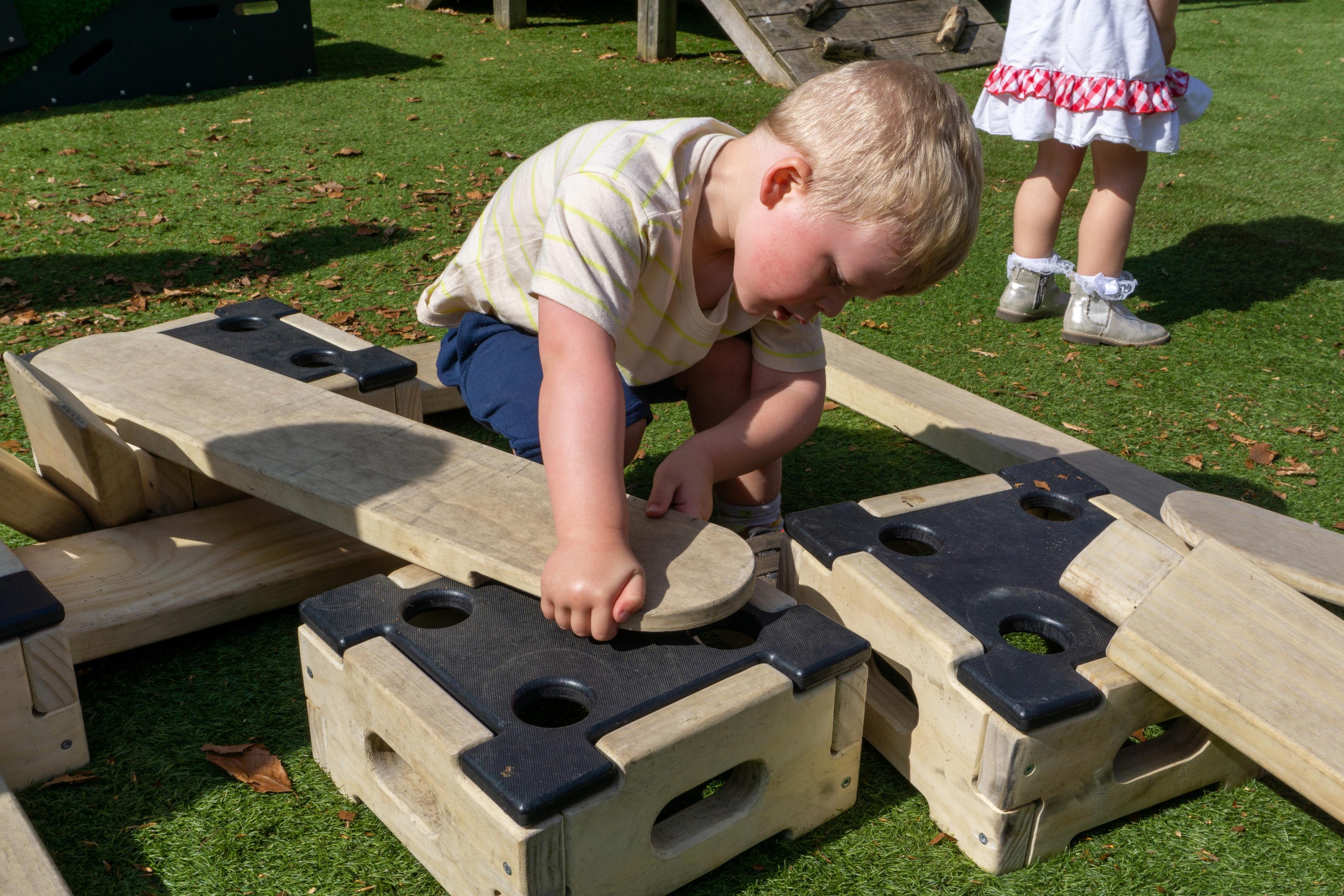 little boy connecting a plank from Play Builder set to a block