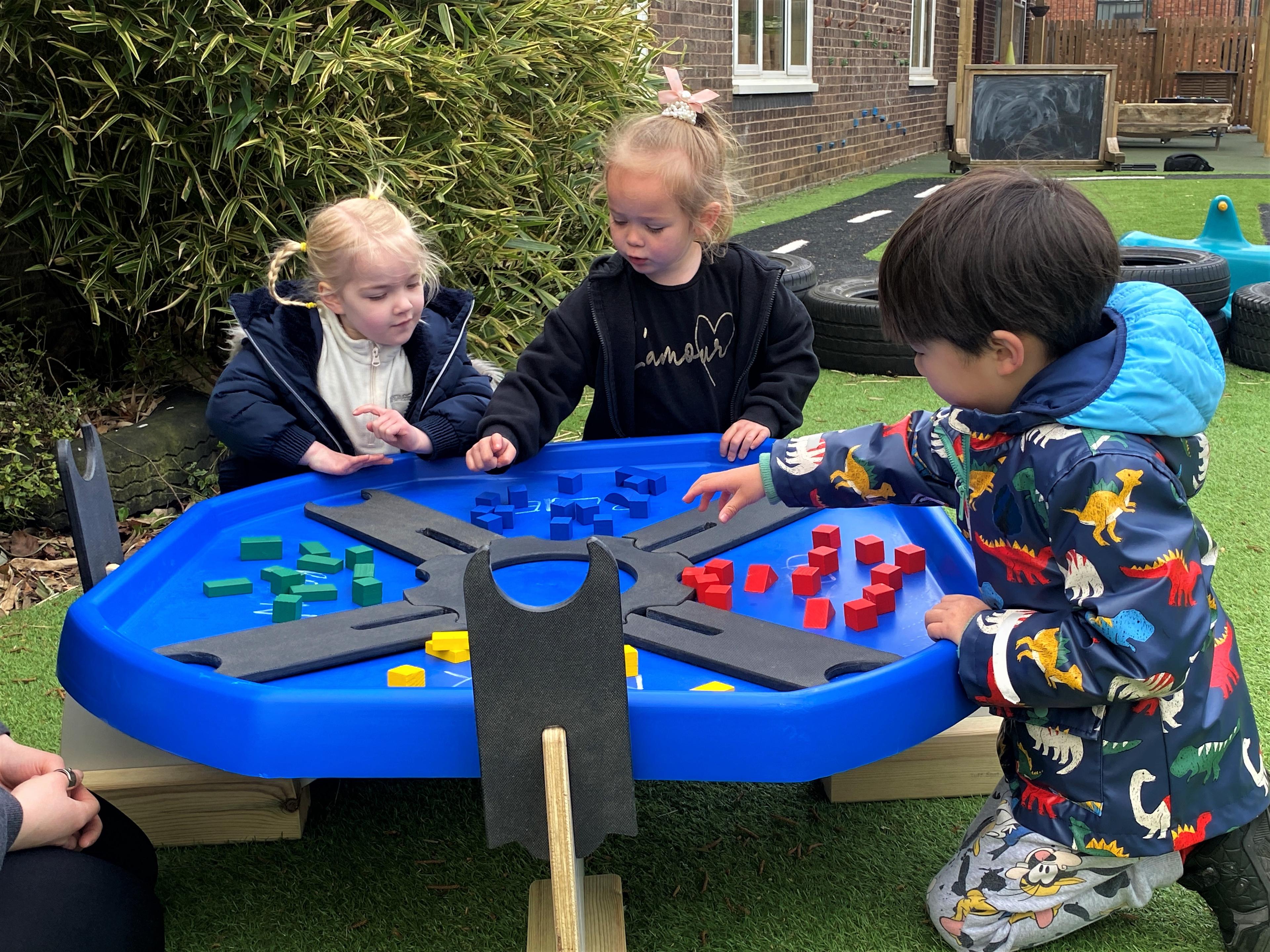 Children dividing up their resources using dividers on a blue plastic table