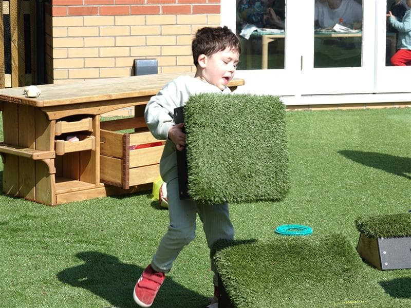 Child moving grass topped block 